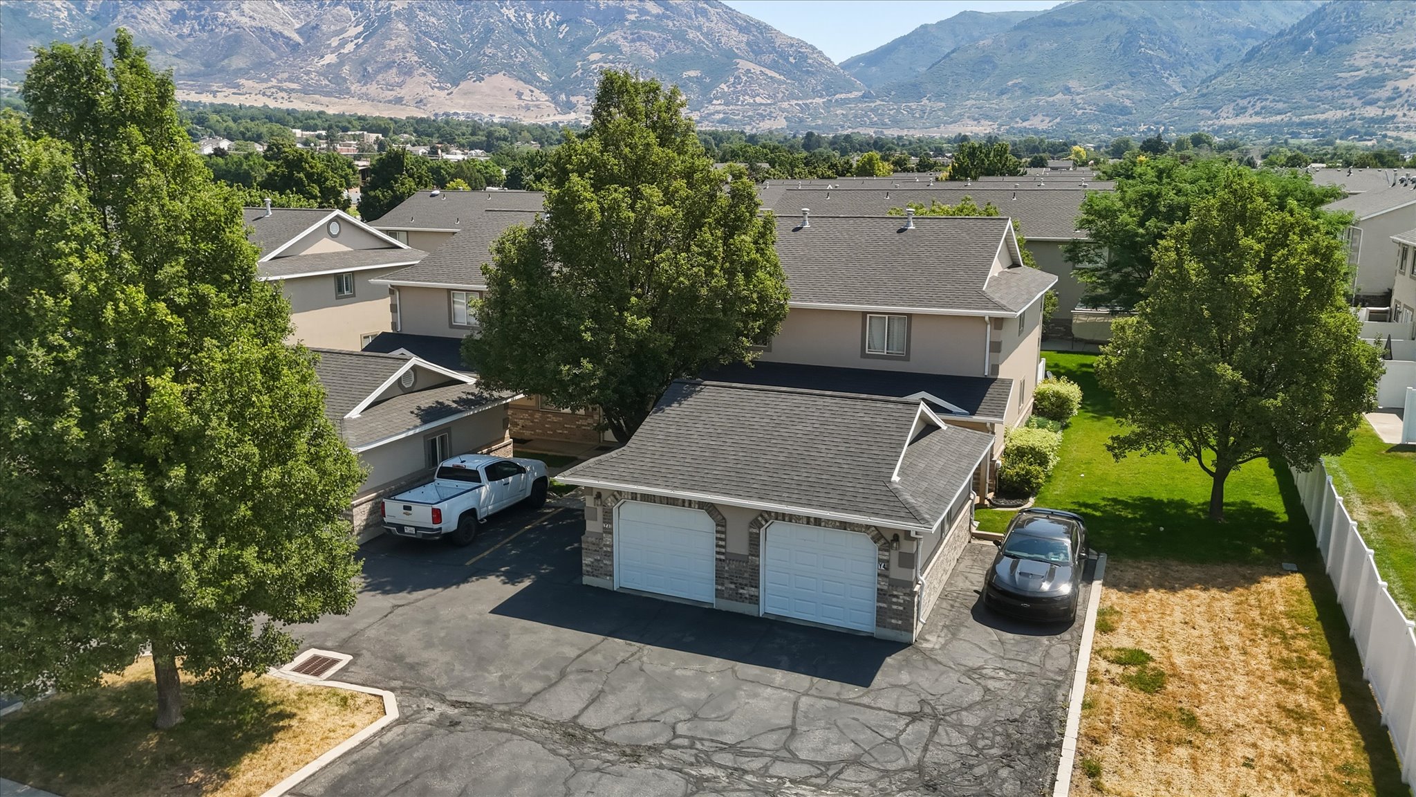 Two-story townhome featuring a dark shingle roof and beige siding