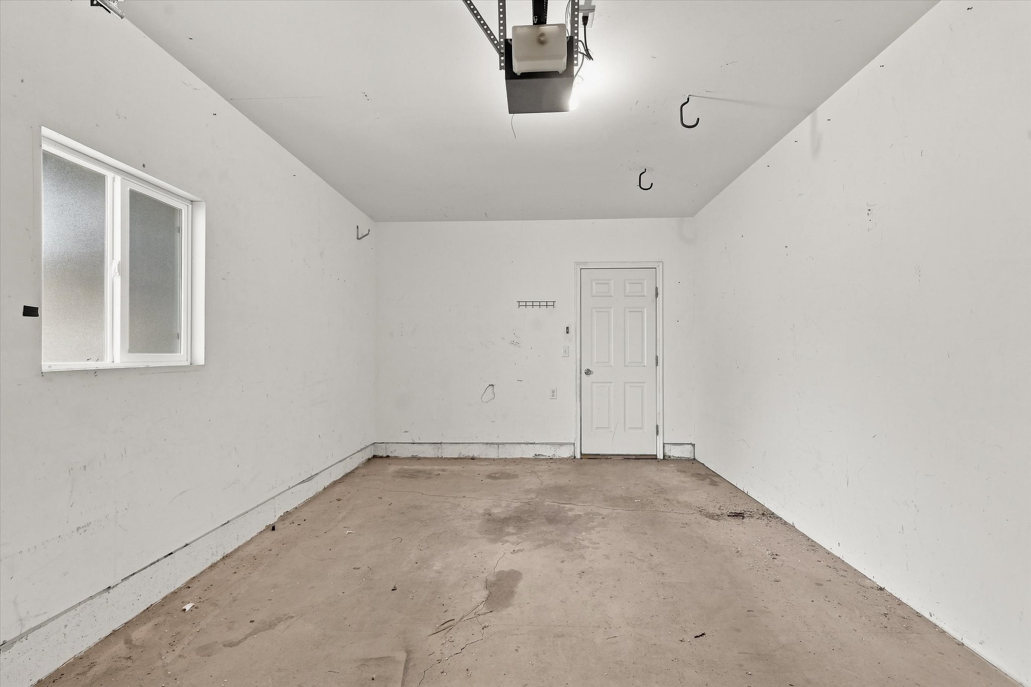Garage space with a window, painted walls, and a service door