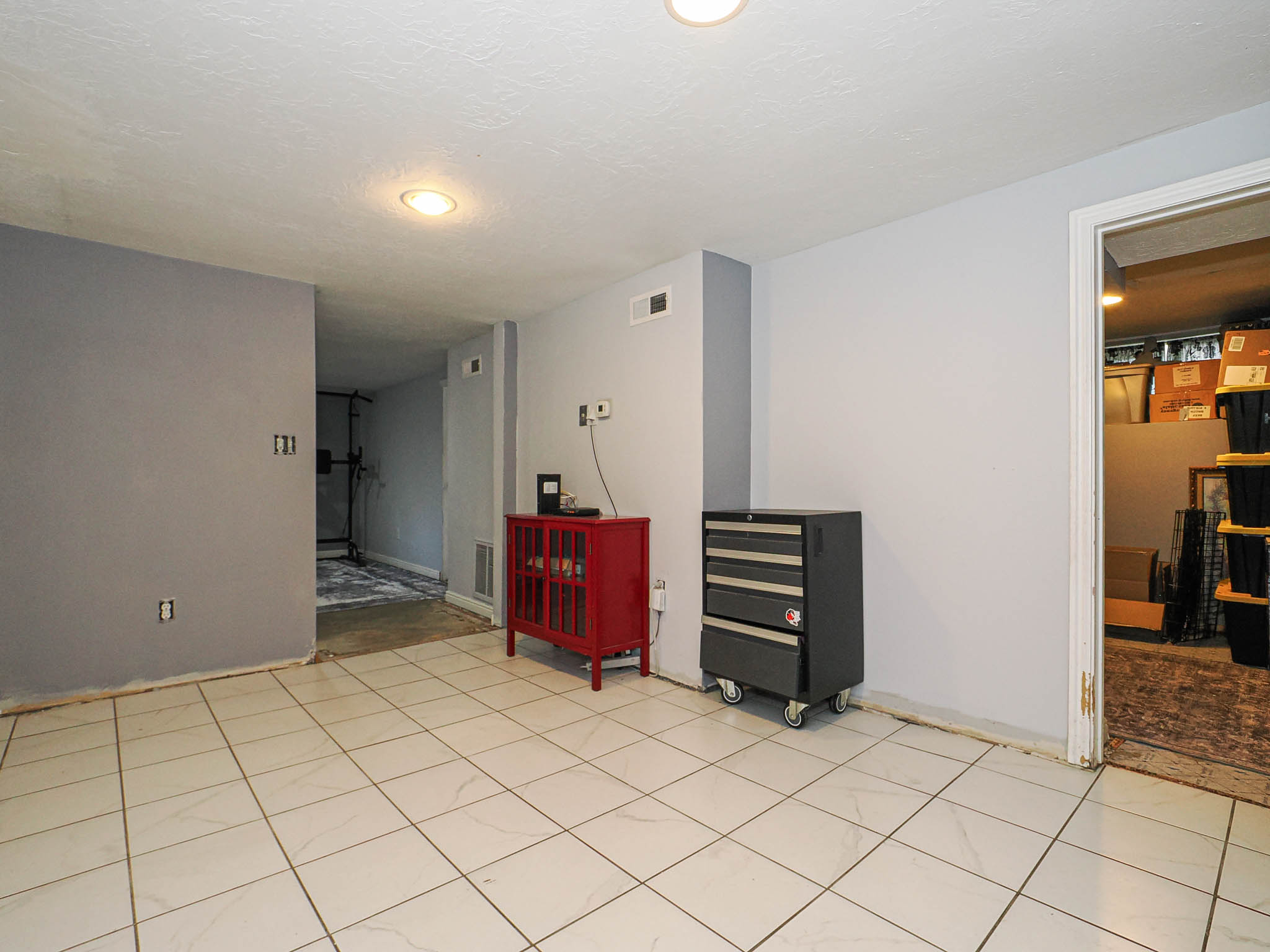 Spacious room featuring light-colored tile flooring, recessed lighting, and a neutral wall palette