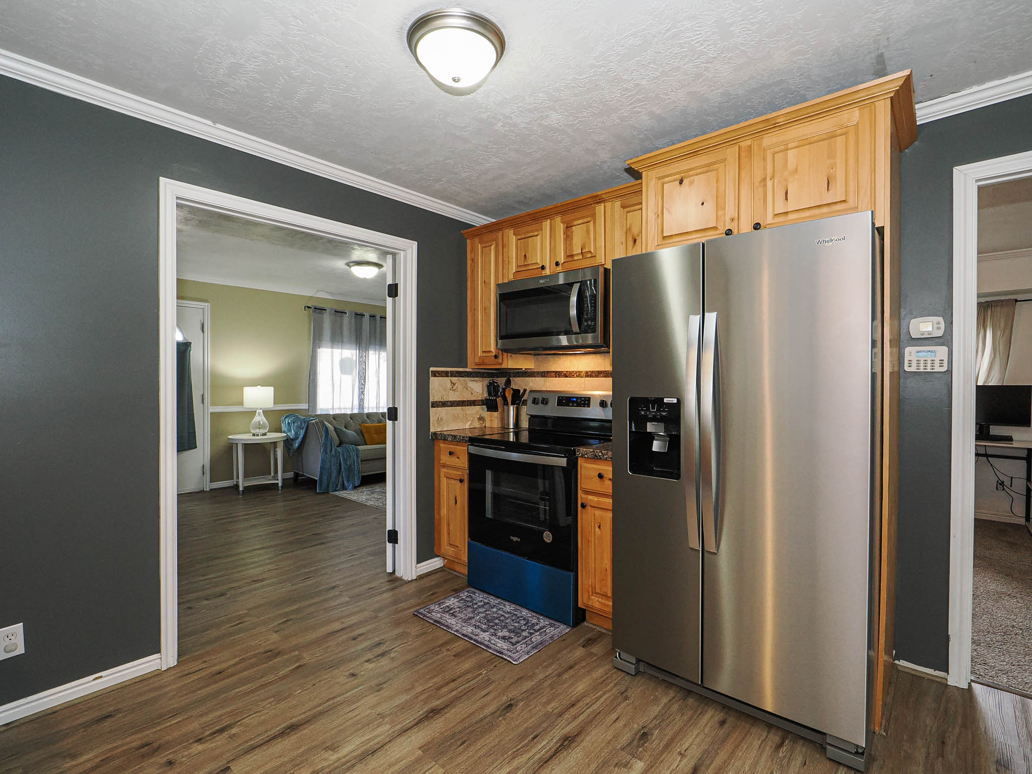 Kitchen featuring wood-finish flooring, natural wood cabinetry, stainless steel appliances, and a stone-tile backsplash