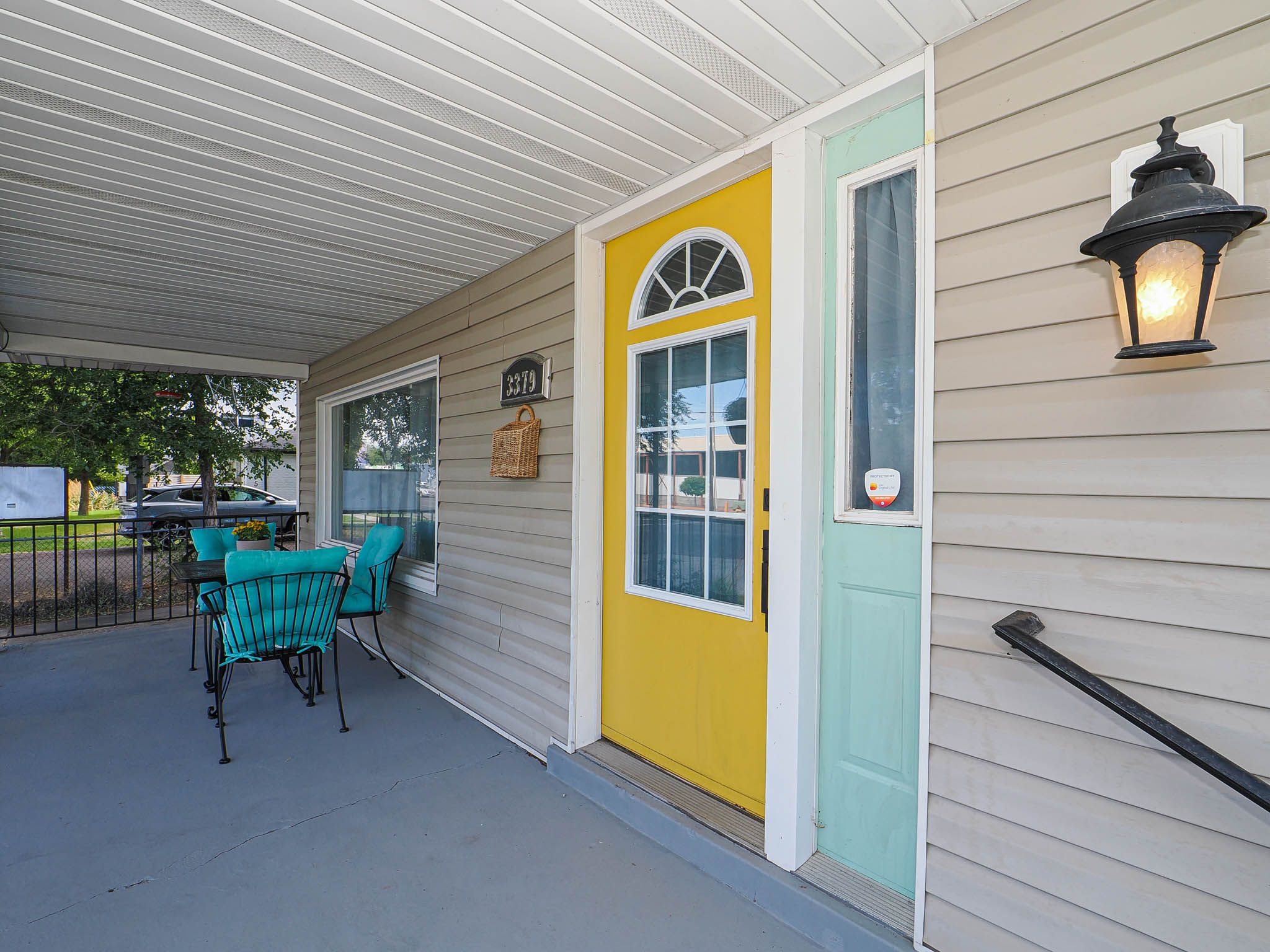 Front porch featuring light gray siding, a bright yellow entry door with an arched transom, and a side light
