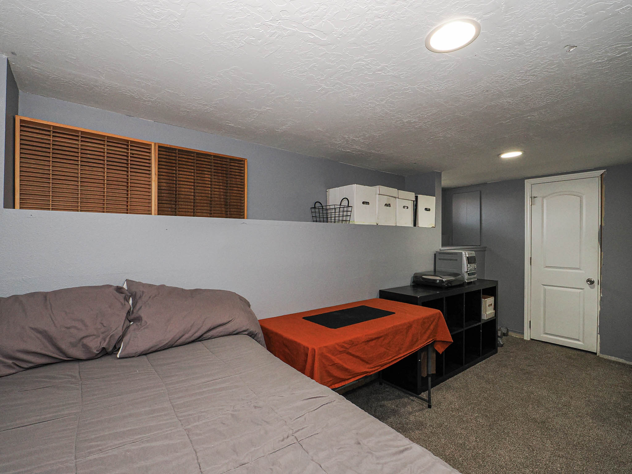 Carpeted room featuring a half-wall with wood louvered accents, recessed lighting, and a white interior door