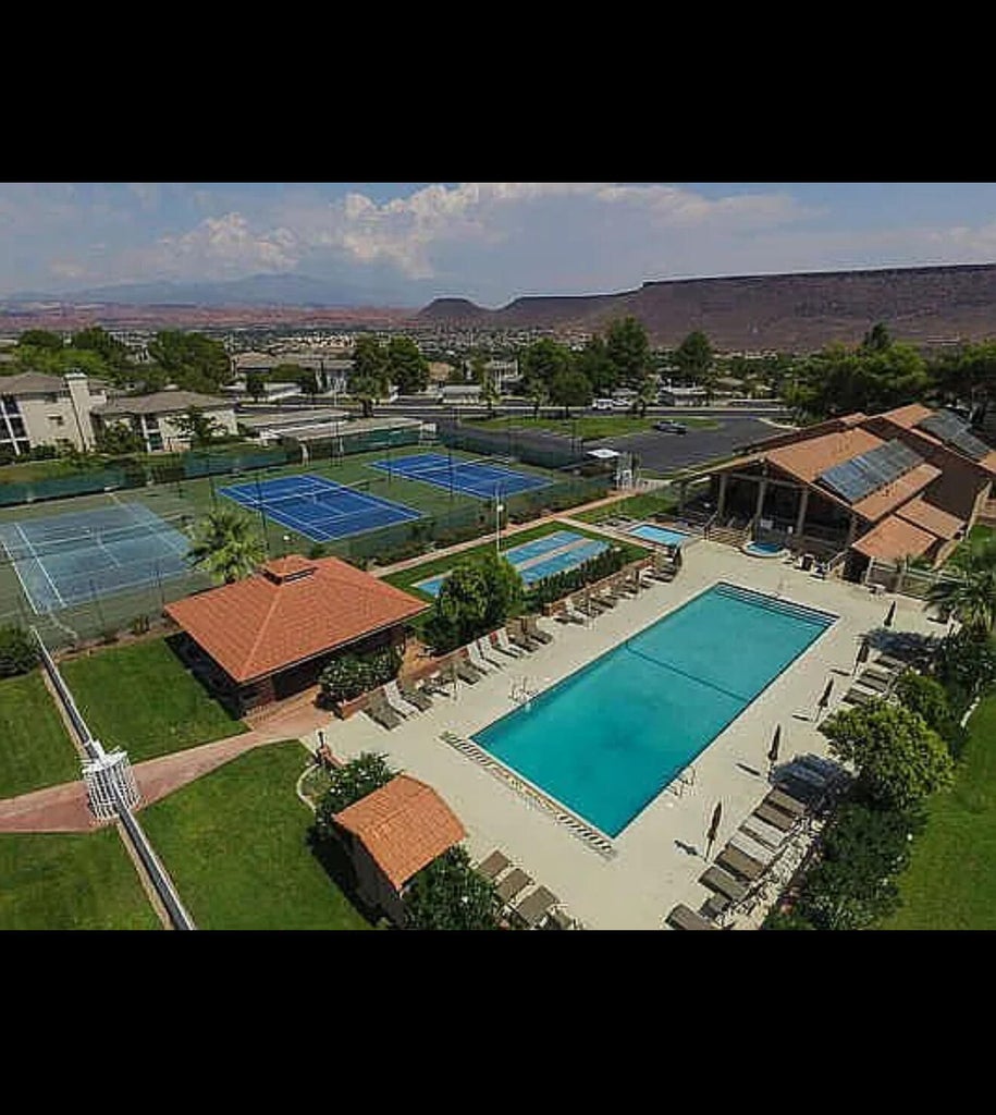 Outdoor recreational complex featuring multiple tennis courts, a large swimming pool, and dedicated lounge areas