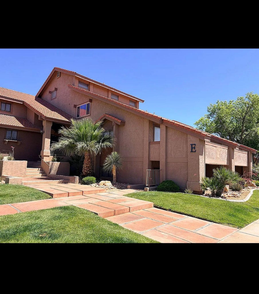 Multi-level stucco exterior featuring a terracotta tile roof and mature desert landscaping