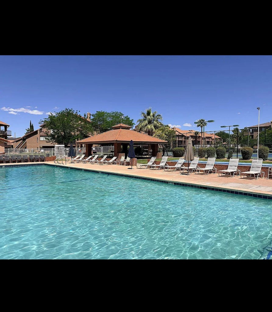 Resort-style aquatic area featuring a large swimming pool with concrete decking, a central shaded gazebo, and surrounding lounge seating