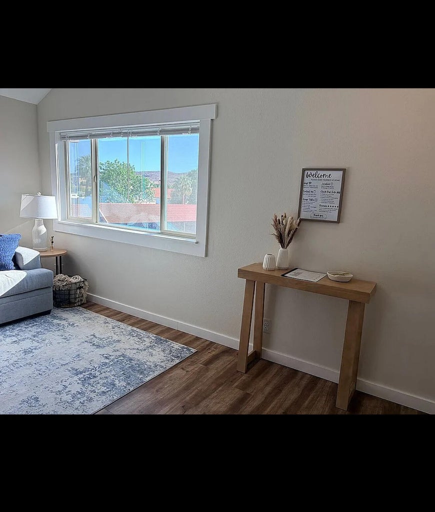 Bright interior space featuring a large window with white trim, wood-finish flooring, and light-toned walls
