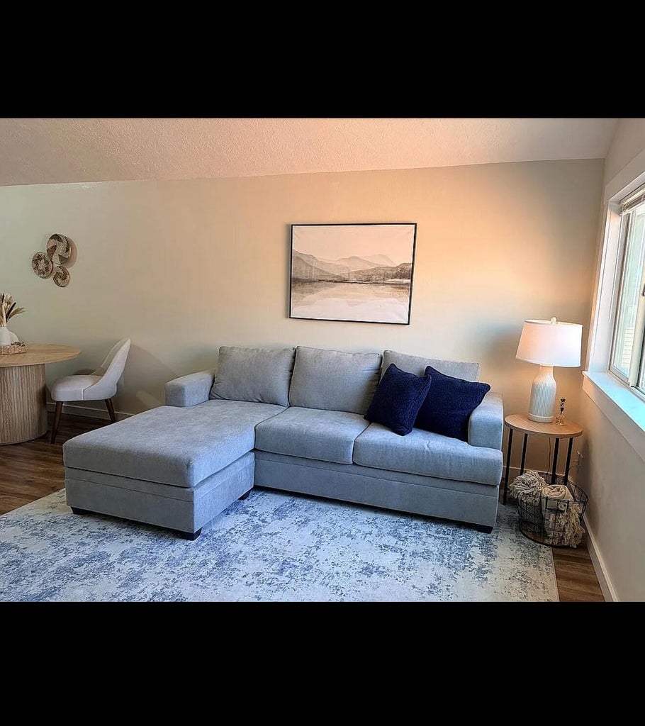 Open-concept living space featuring wood-finish flooring, light-toned walls, and a large window providing natural illumination