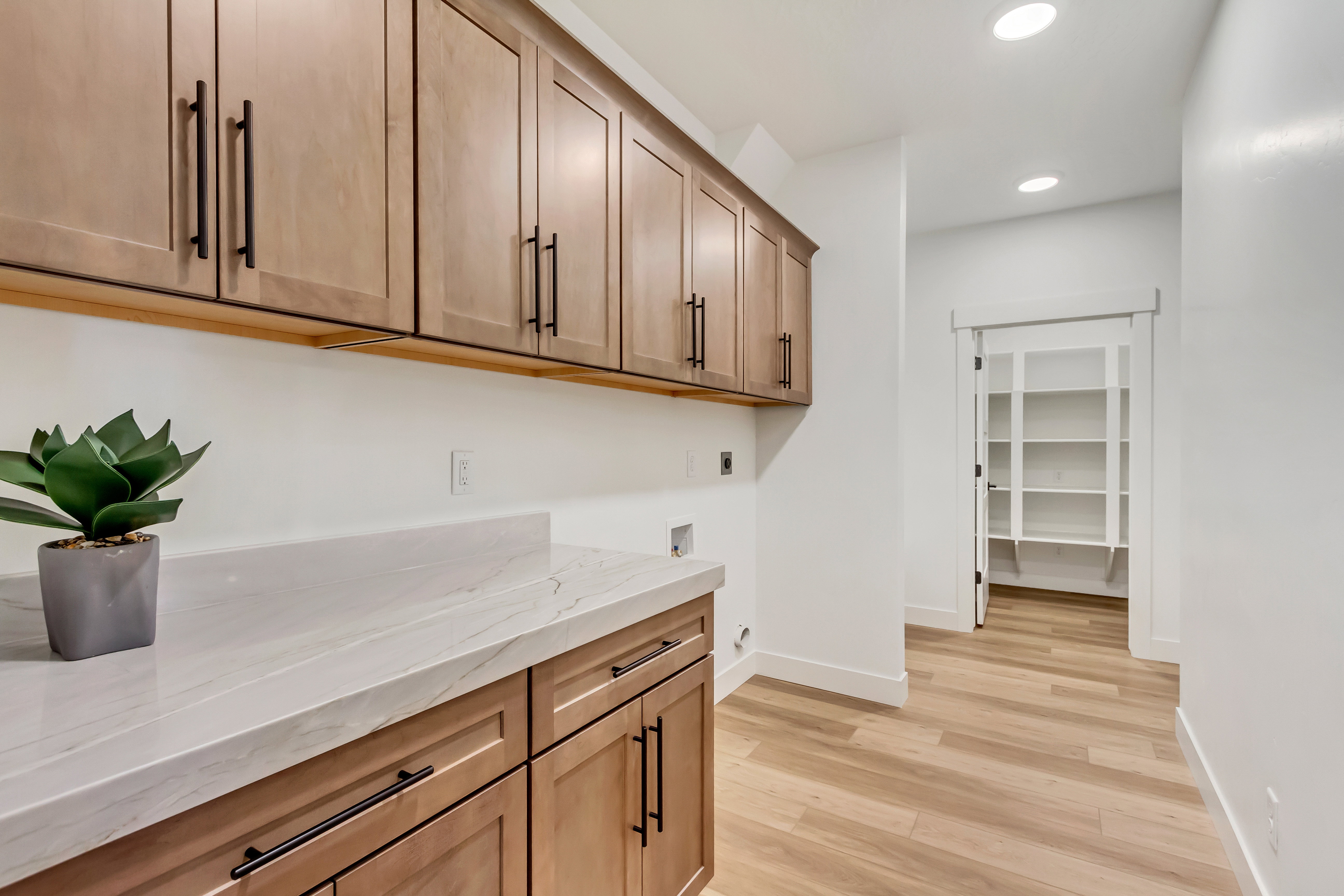Expansive laundry and utility space featuring light wood-finish cabinetry, a large light-toned countertop, and recessed lighting