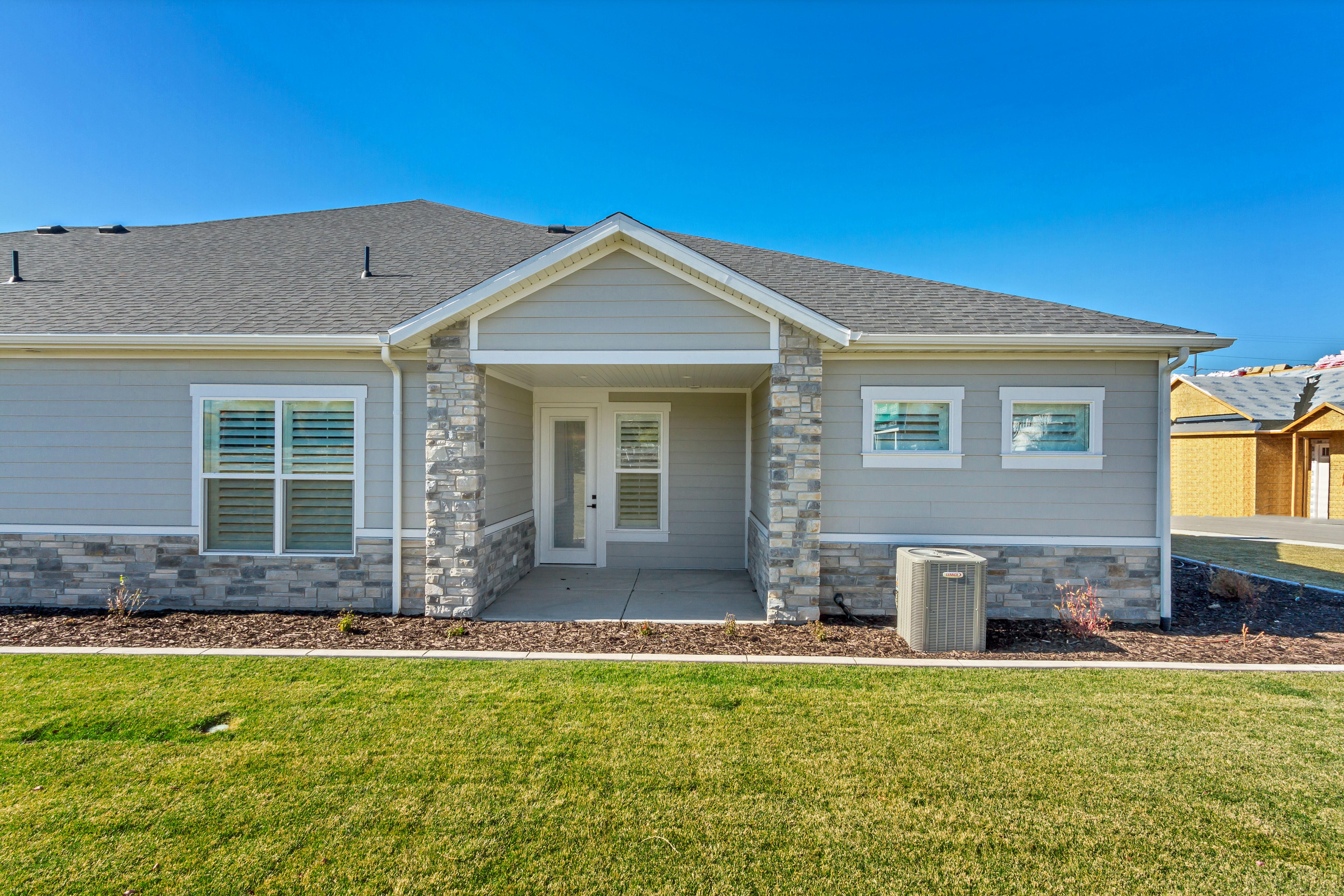 Single-story residence featuring light gray siding with a stone veneer accent, a covered entryway, and a gray shingle roof