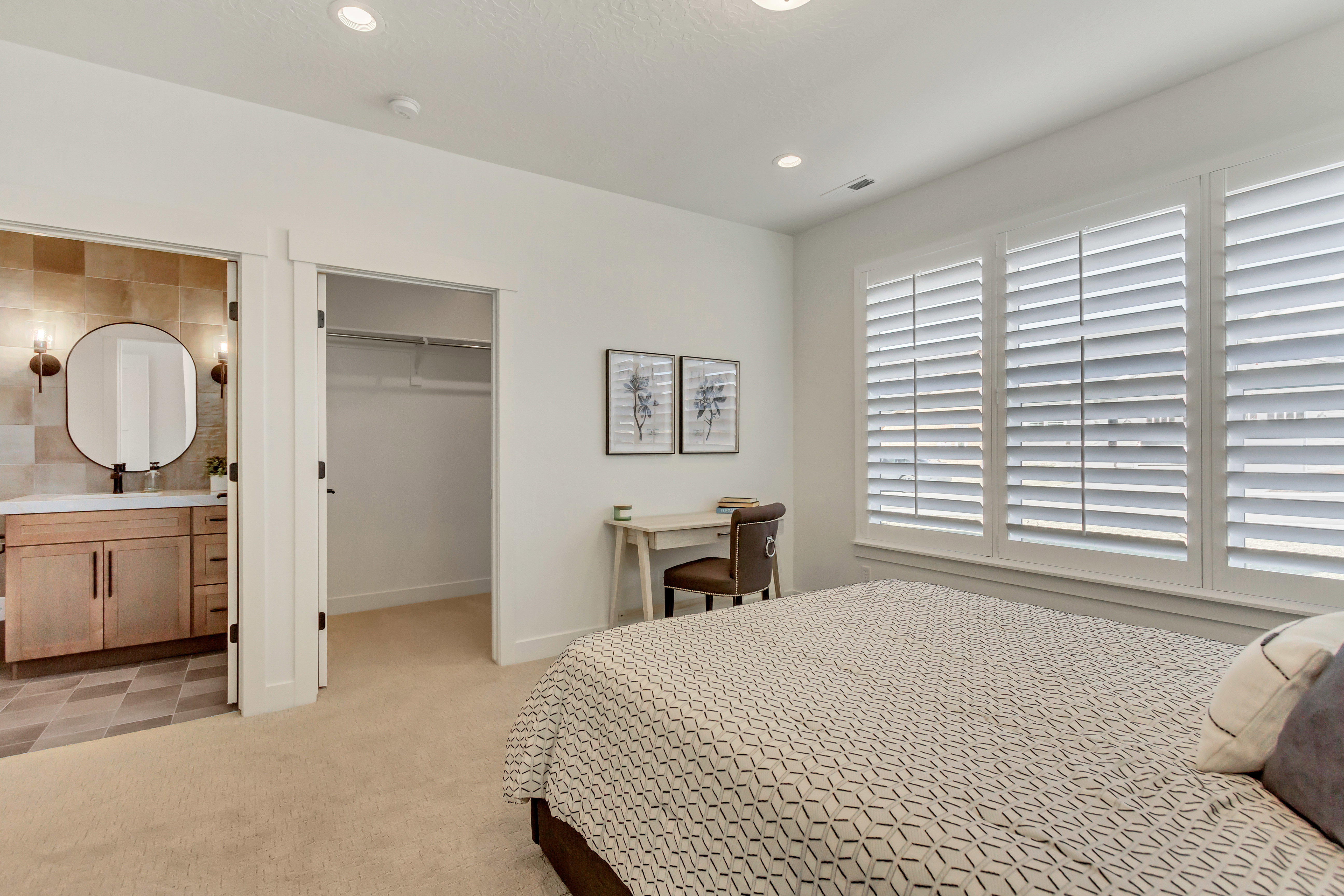 Neutral-toned bedroom featuring recessed lighting, a window fitted with white plantation shutters, and light-colored carpeting