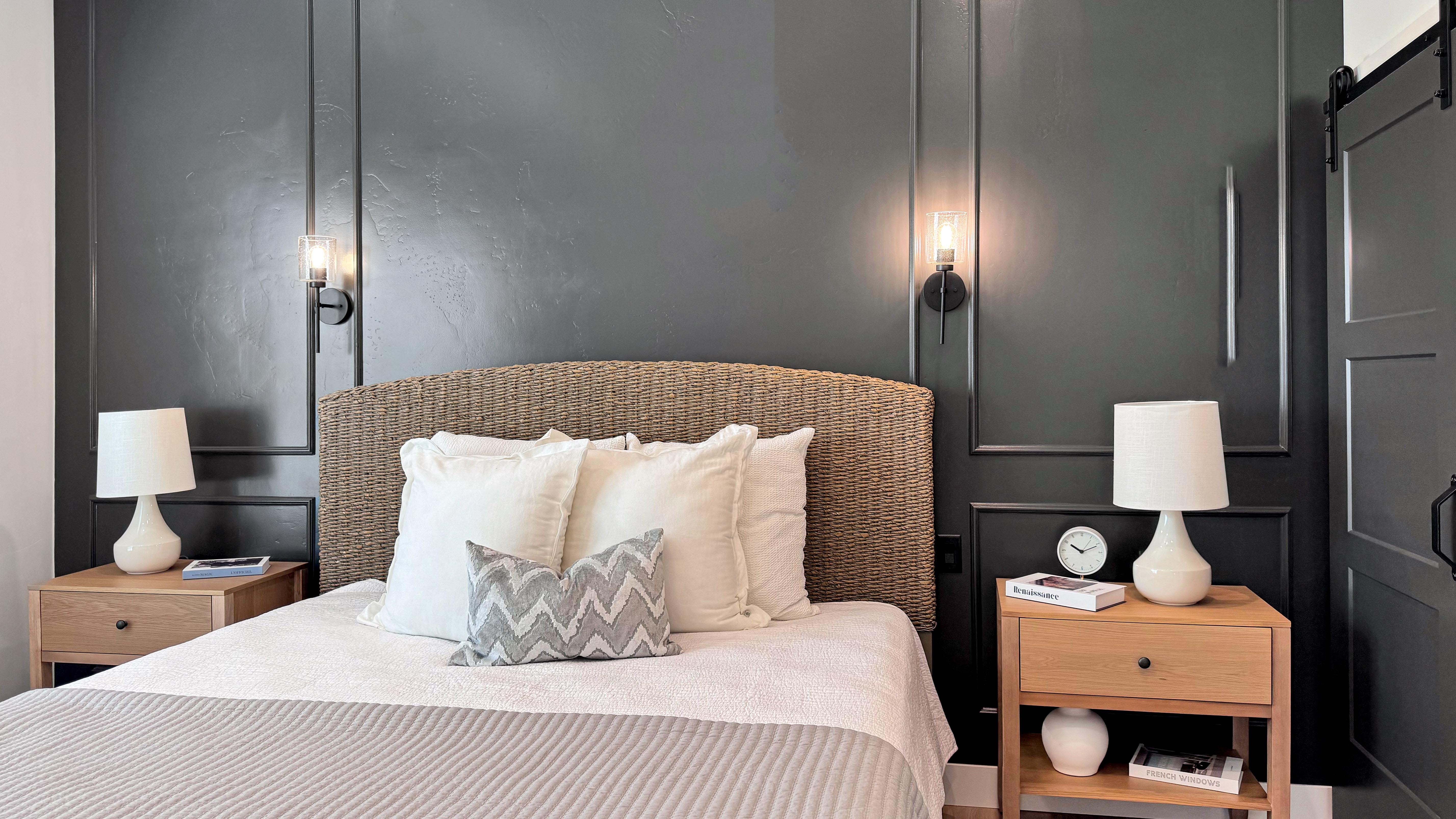 Dark accent wall with decorative molding, wall-mounted sconce lighting, and a sliding barn door