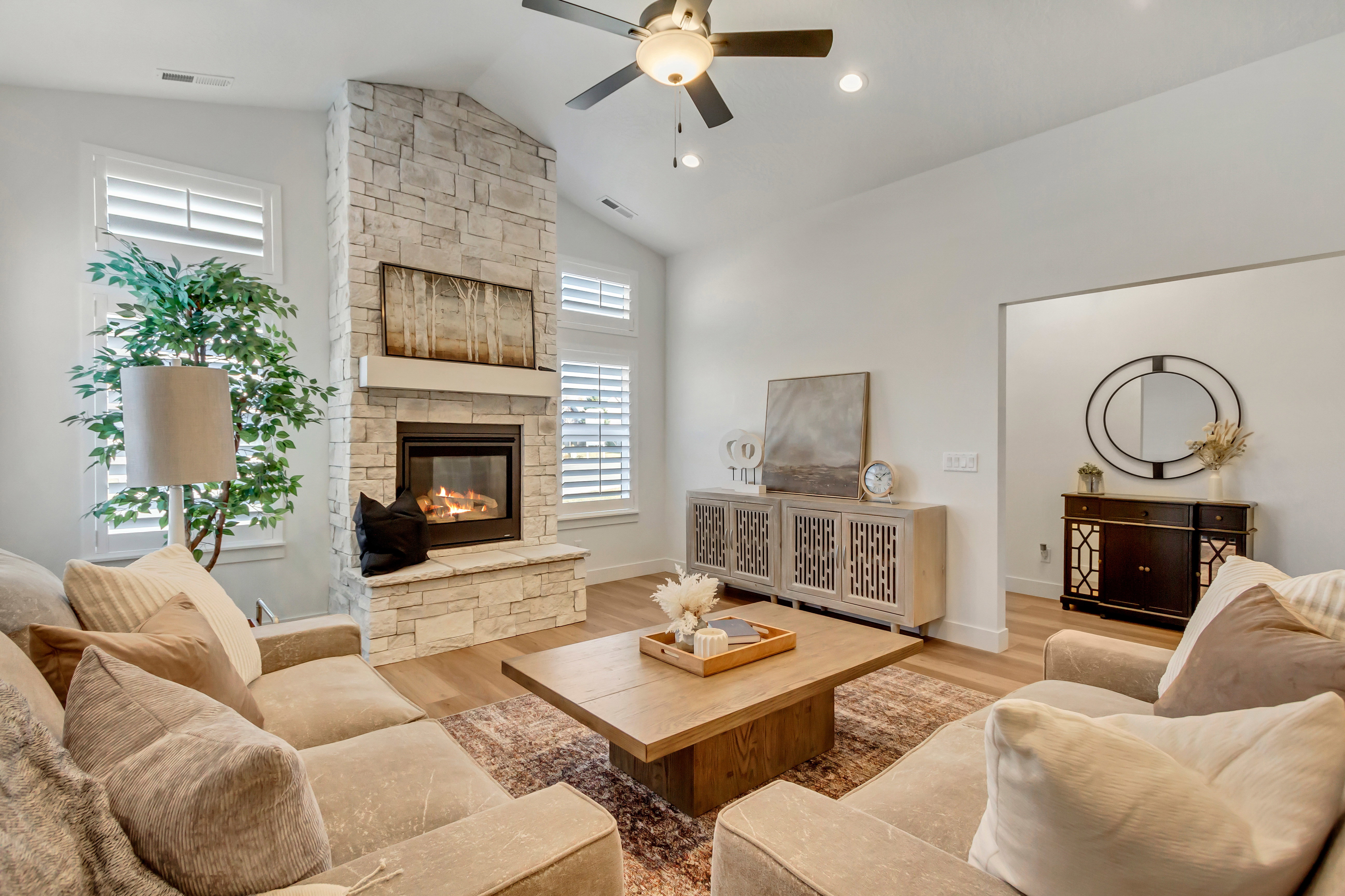 Spacious living area featuring a vaulted ceiling and a stone-clad fireplace with a built-in mantel
