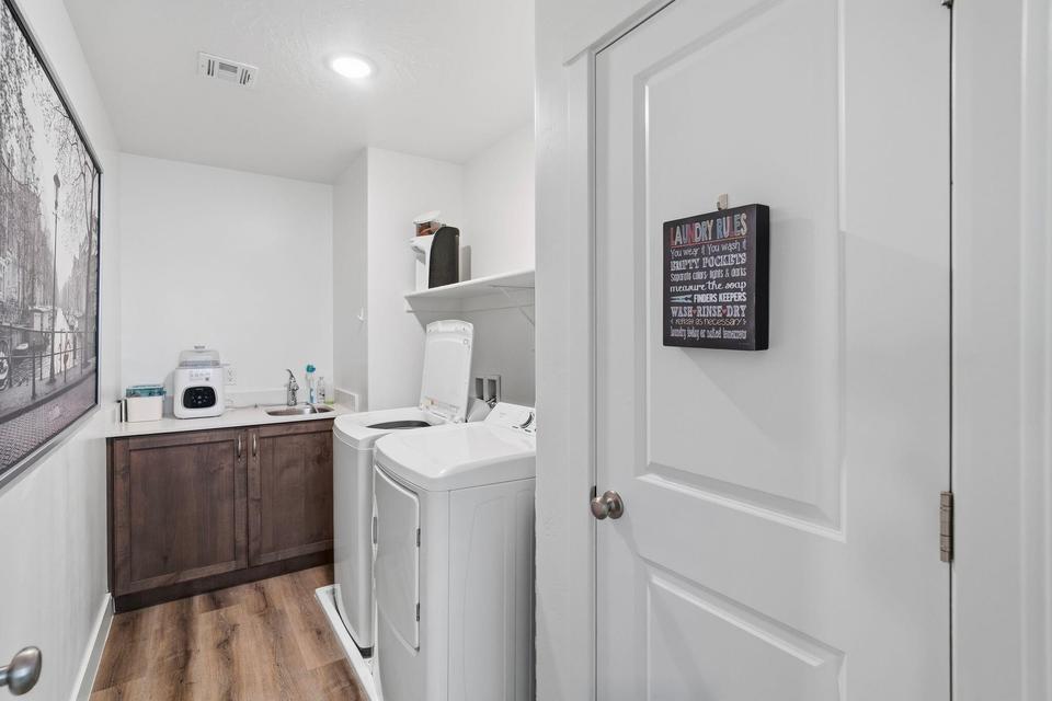 Dedicated laundry space featuring wood-finish flooring, white walls, and bright overhead lighting