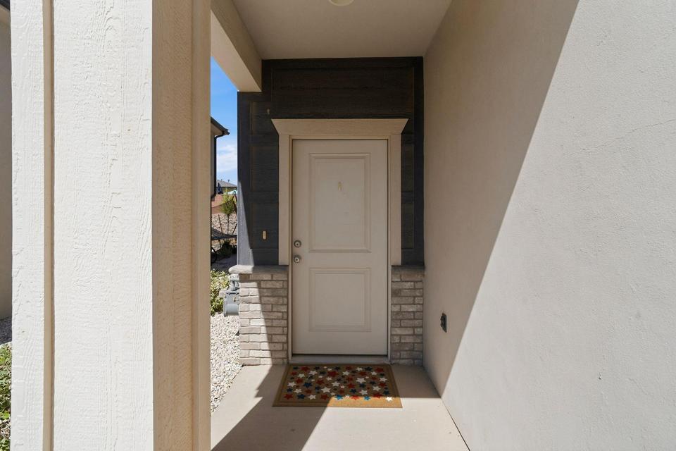 Covered entry featuring a paneled door, stone facade accents, dark horizontal siding, and textured exterior walls
