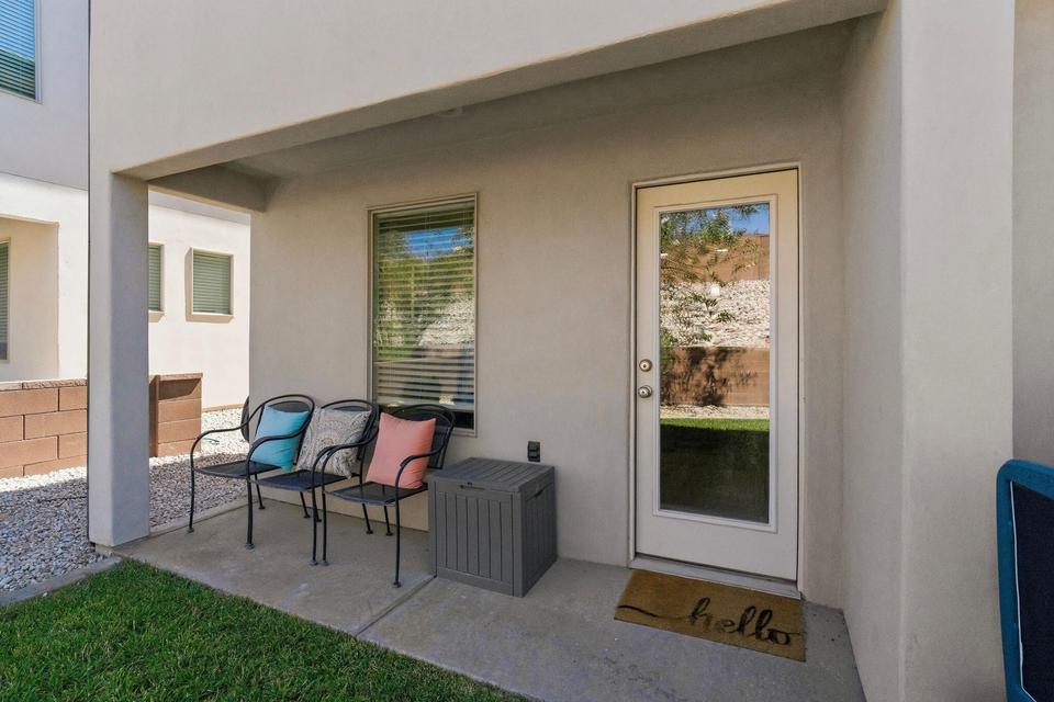 Private covered patio featuring a full-light exterior door, a large window with horizontal blinds, and a concrete patio surface