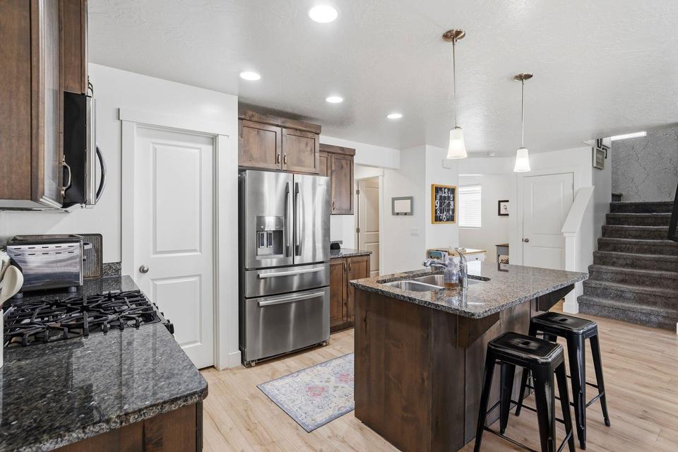Gourmet kitchen featuring wood-finish cabinetry, granite countertops, stainless steel appliances, and a central island with integrated sink