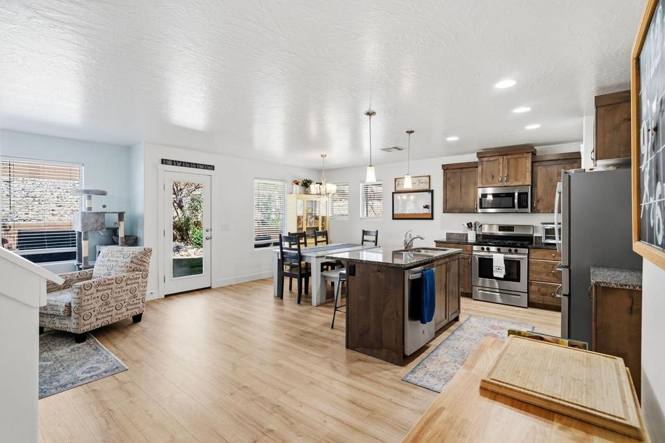 Open-concept kitchen and dining area featuring wood-finish flooring, recessed lighting, and stainless steel appliances