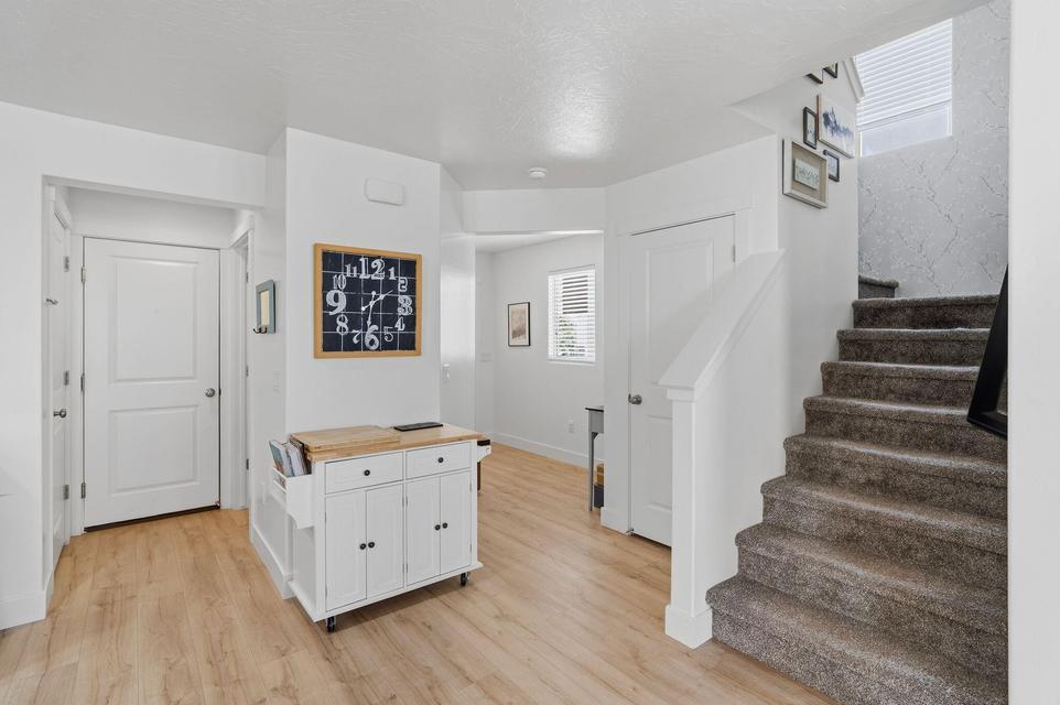 Entryway featuring wood-finish flooring, white paneled doors, and a carpeted staircase