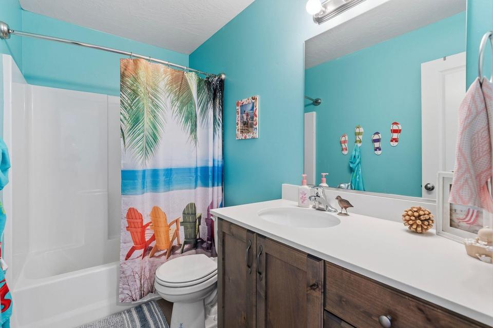 Bathroom featuring a wood-finish vanity with a white countertop, an undermount sink, and a large wall-mounted mirror