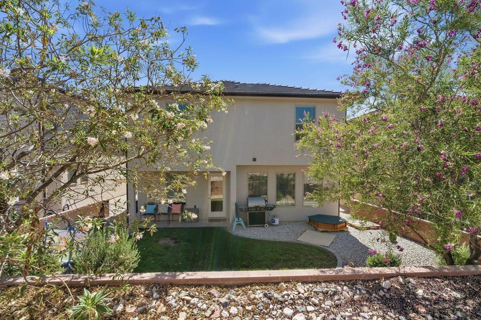 Rear exterior featuring a stucco facade, multiple windows, and a partially covered patio