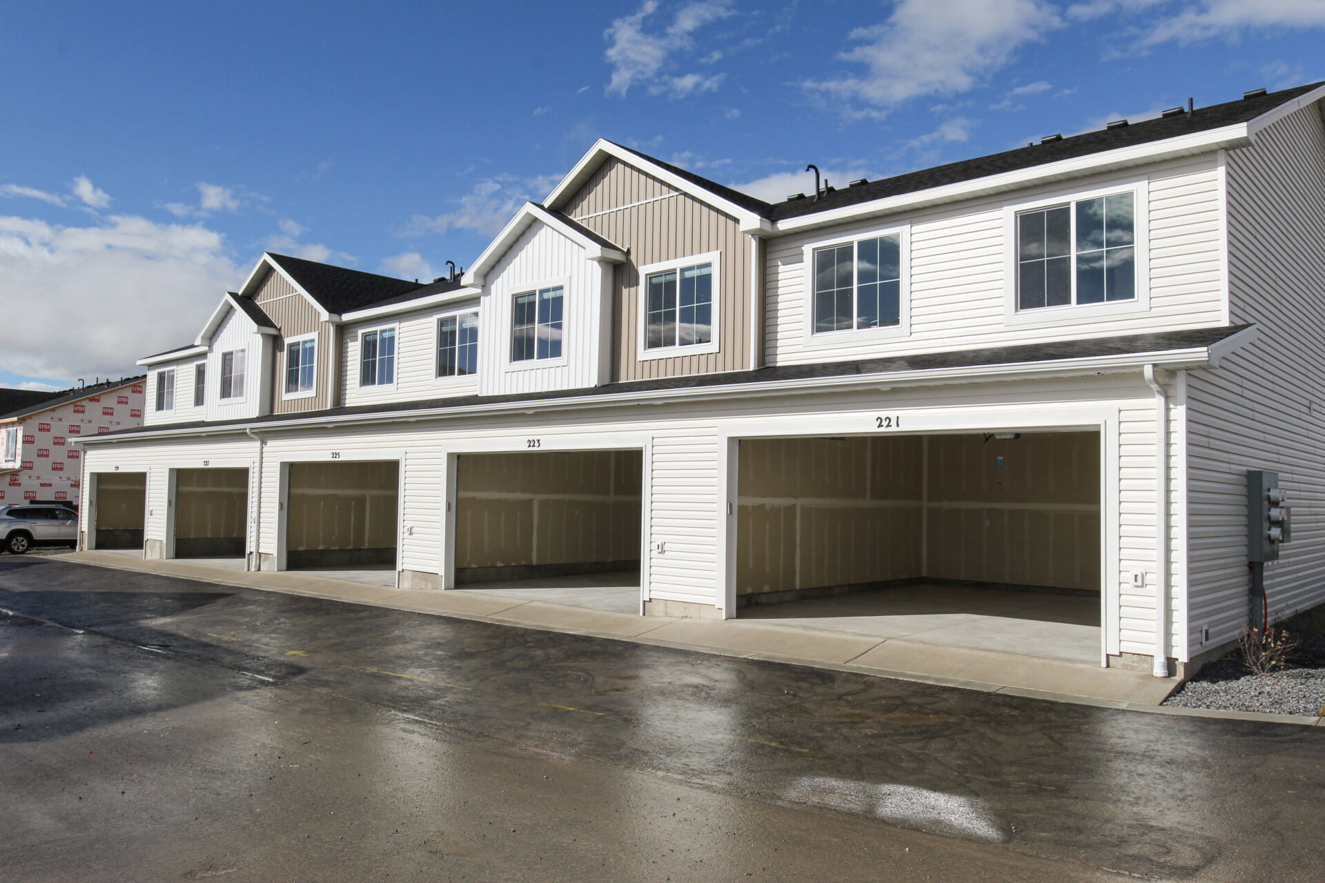 Multi-unit residential exterior featuring white horizontal siding and contrasting beige vertical siding