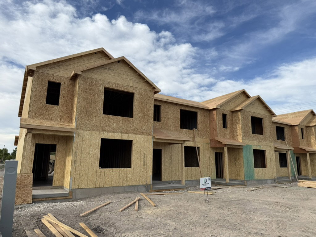 New construction townhomes featuring framed exteriors, multiple window openings, and covered entryways