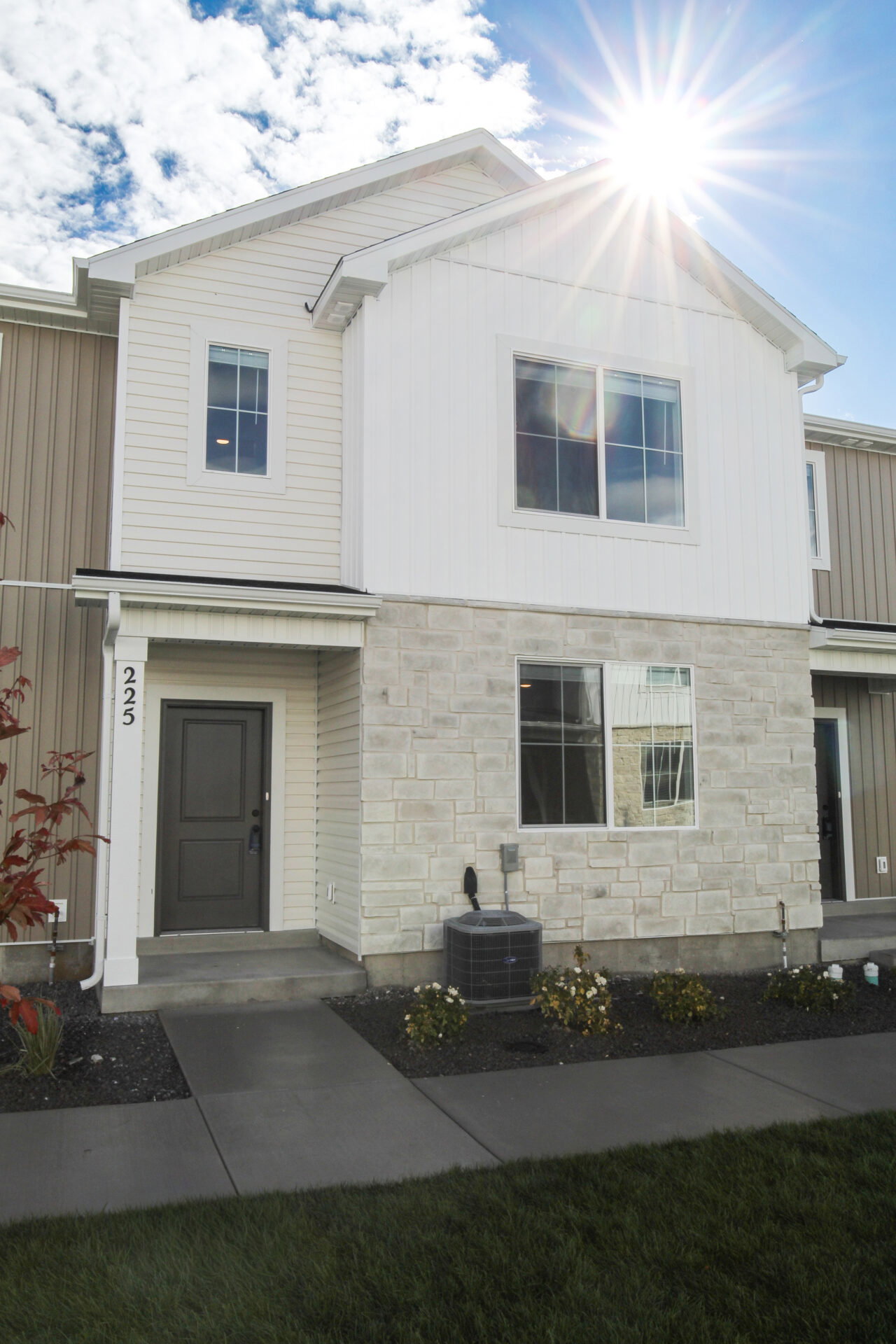 Contemporary townhome exterior featuring light-toned siding and a stone facade