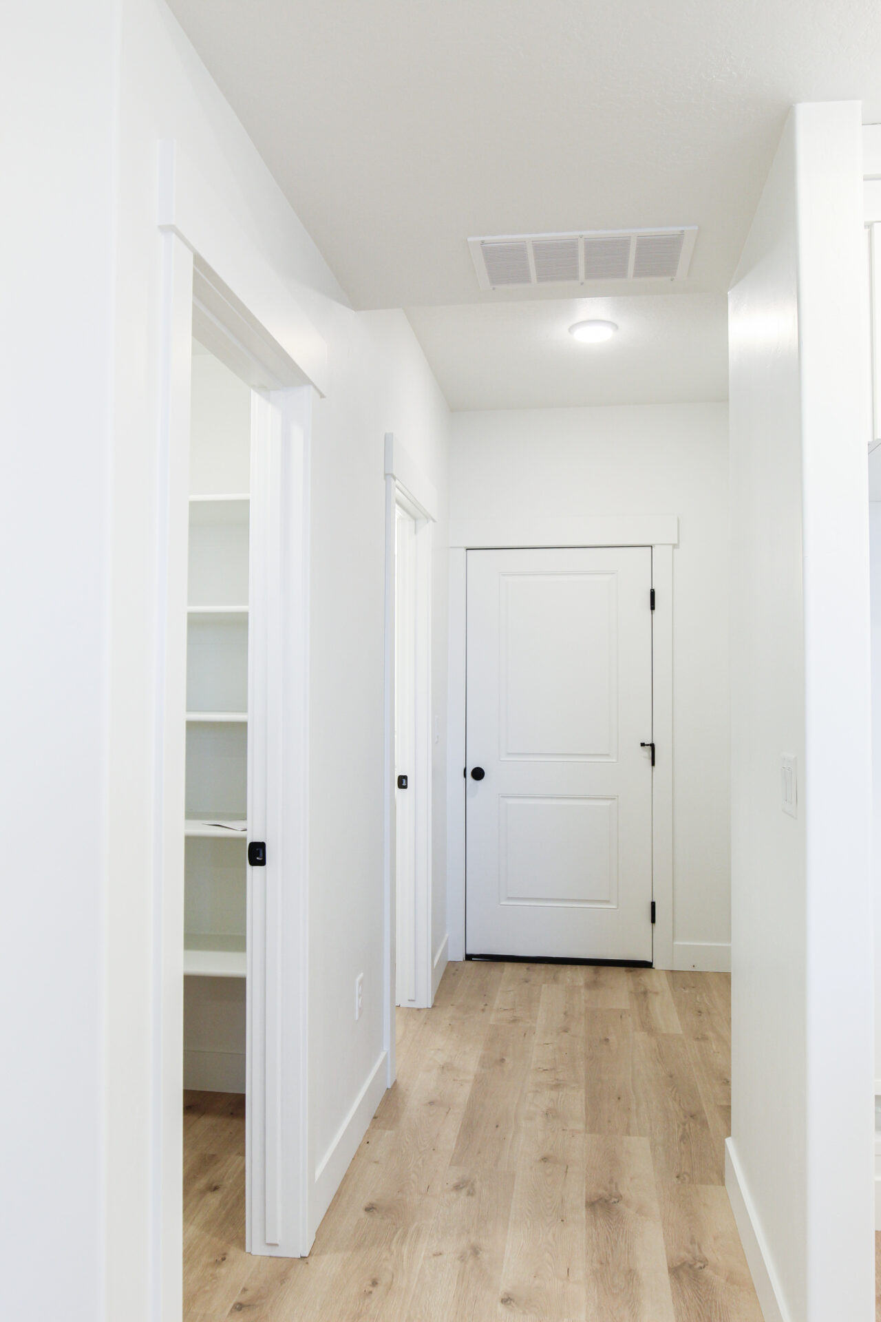 Hallway featuring light wood-finish flooring, white walls, and a ceiling-mounted light fixture