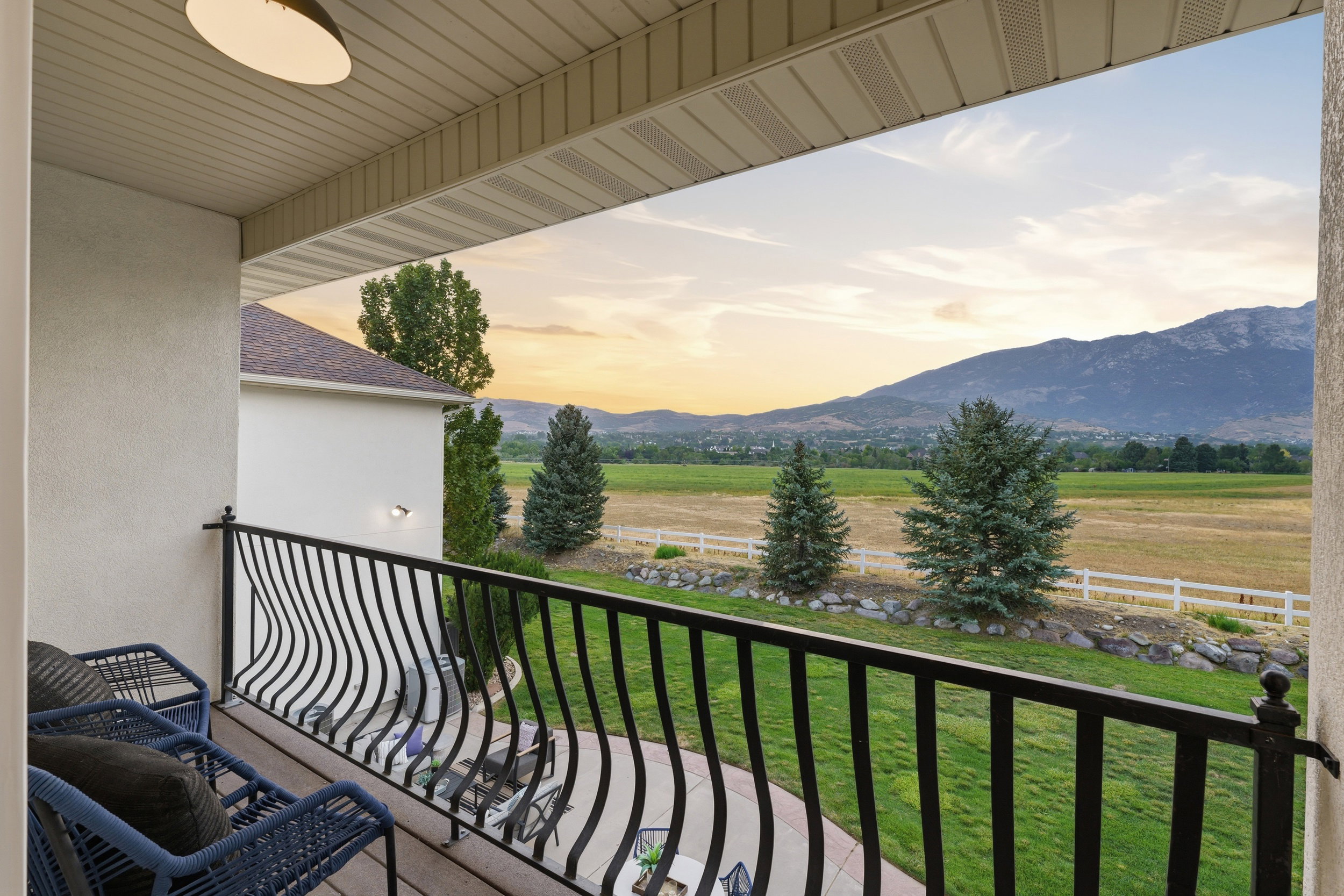 Balcony featuring a decorative black metal railing, offering expansive scenery with fields and mountains