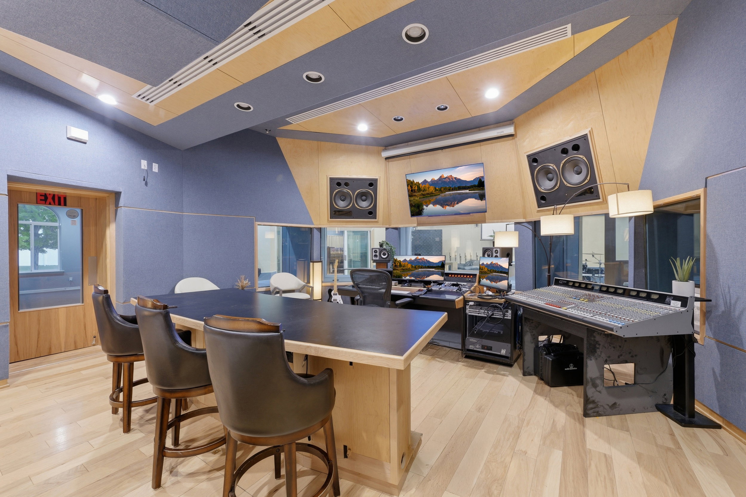 Professional recording studio with acoustic paneling, wood-finish flooring, recessed lighting, and integrated sound equipment