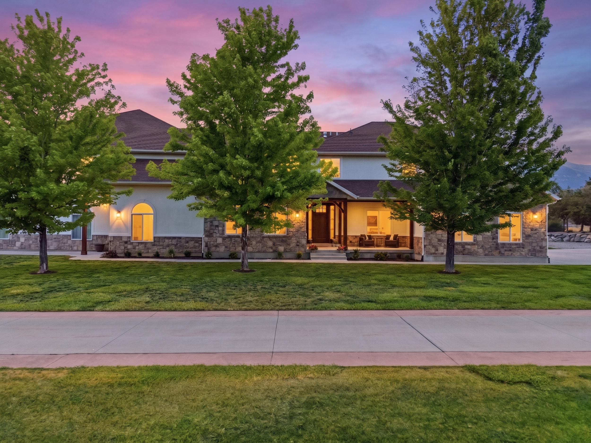 Stucco and stone exterior featuring a covered front porch, arched windows, and a concrete paver walkway