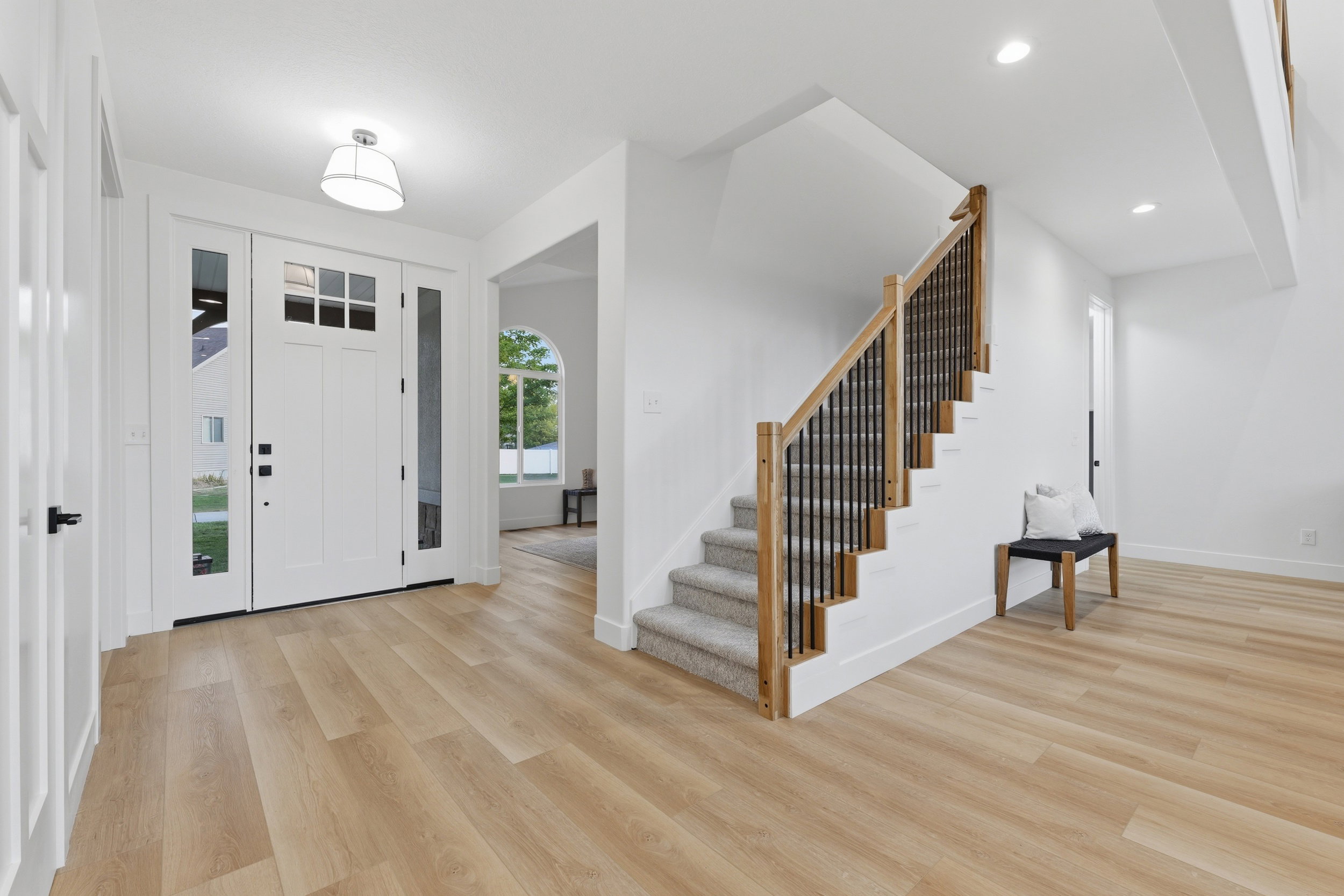 Bright entryway featuring wood-finish flooring and a white front door with sidelights