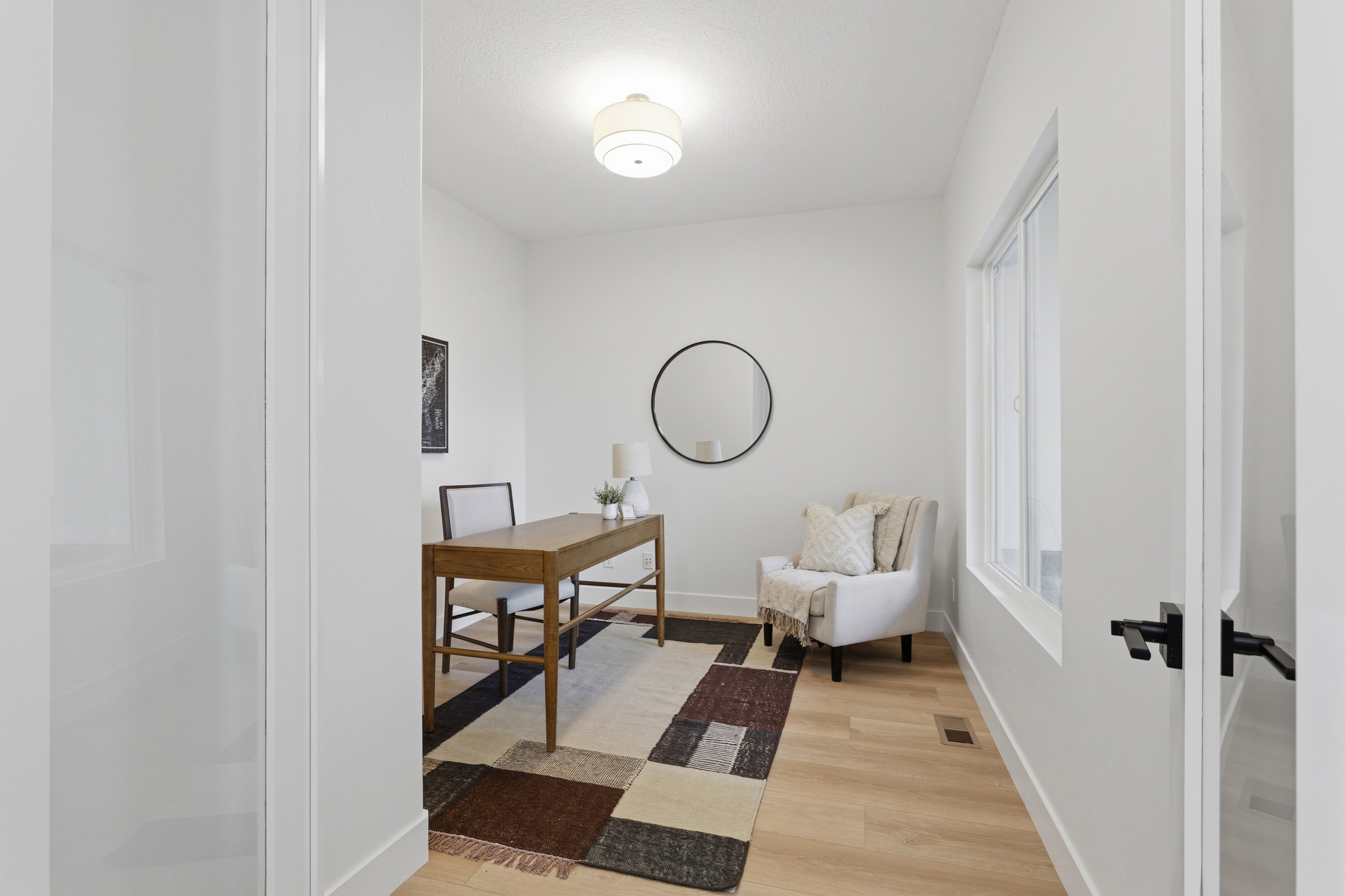 Bright room featuring light wood-finish flooring, white walls, and a contemporary flush-mount ceiling light