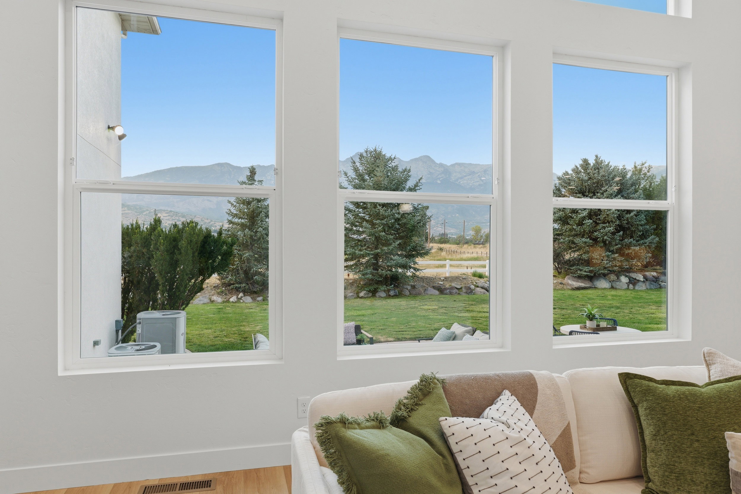 Spacious living area featuring large windows, white trim, and wood-finish flooring