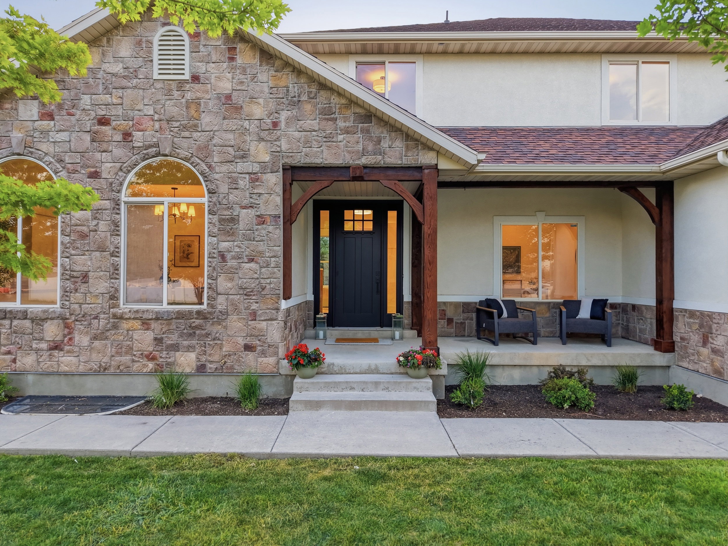 Stone veneer and stucco exterior with a covered entry porch featuring decorative wood beams