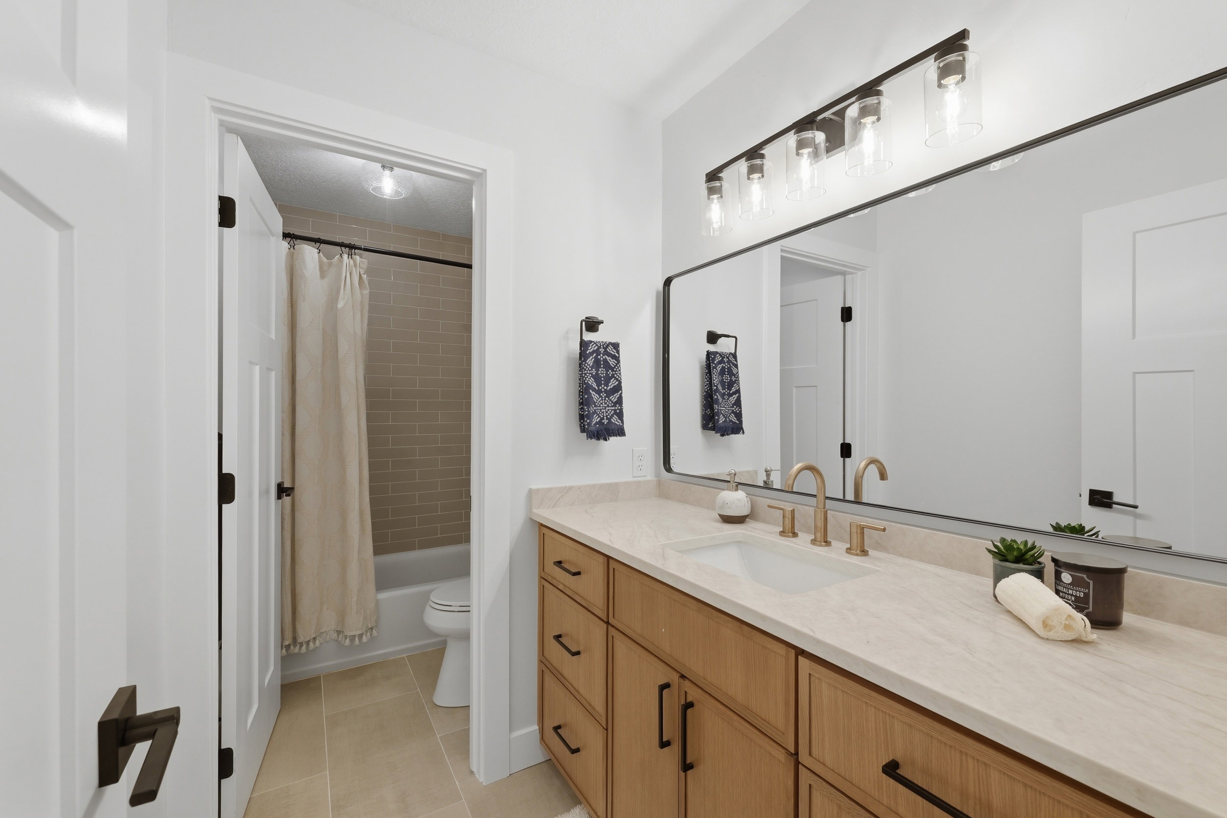 Bathroom featuring a single vanity with wood-finish cabinetry, a light-toned countertop, and gold-finish fixtures