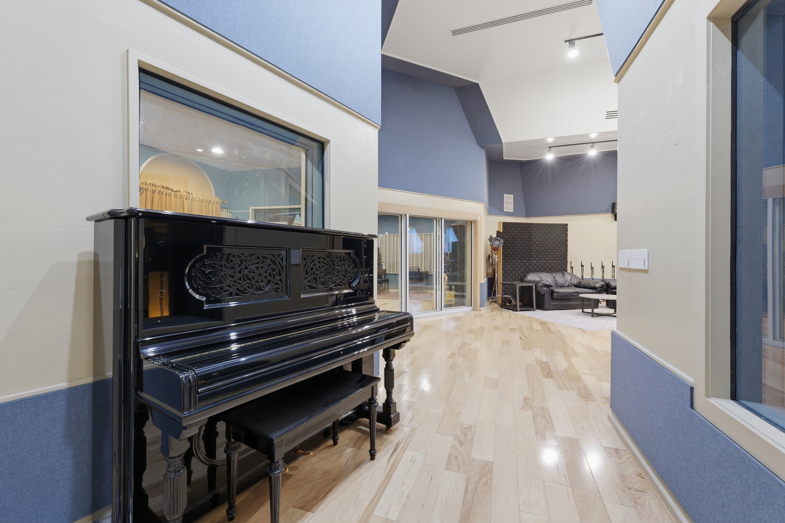 Sound-engineered space featuring light wood-finish flooring, acoustic wall panels, and built-in viewing windows