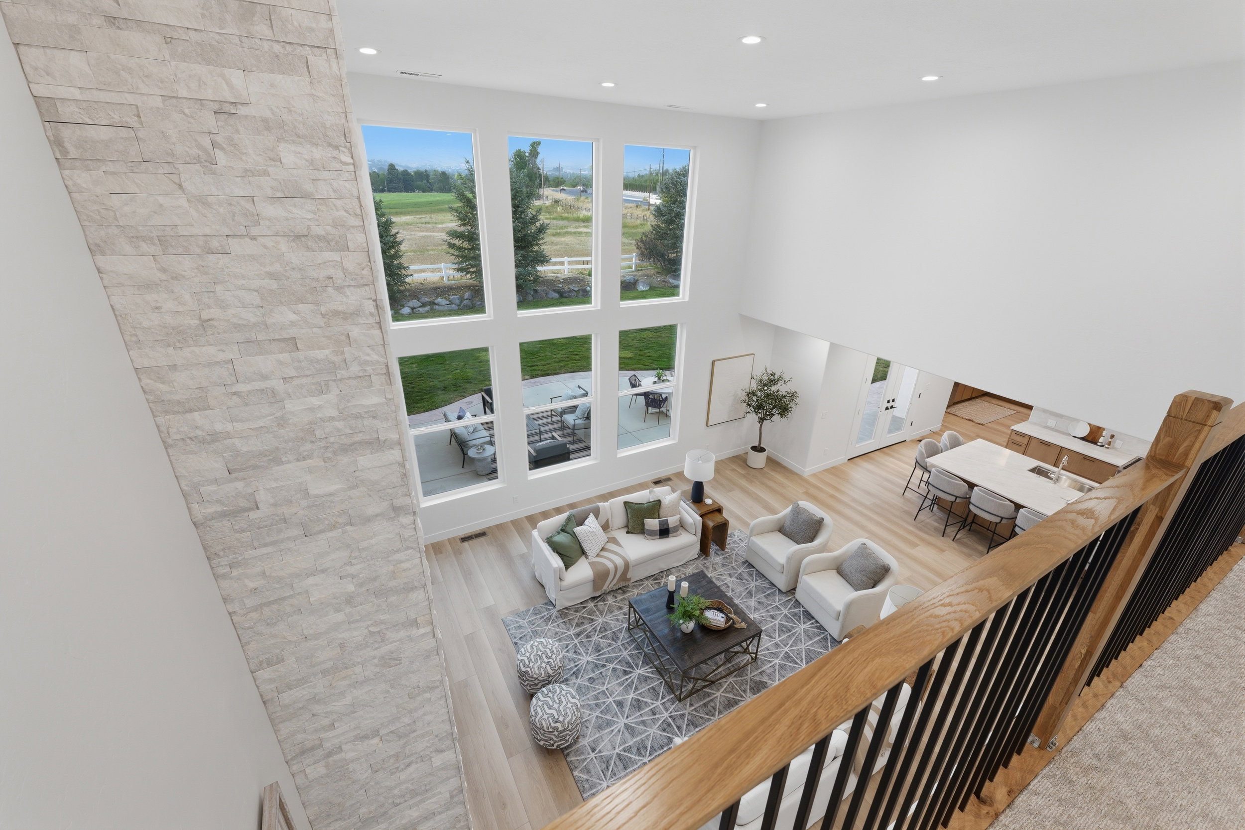 Open-concept living area with a stone-clad accent wall, soaring ceilings, and expansive windows