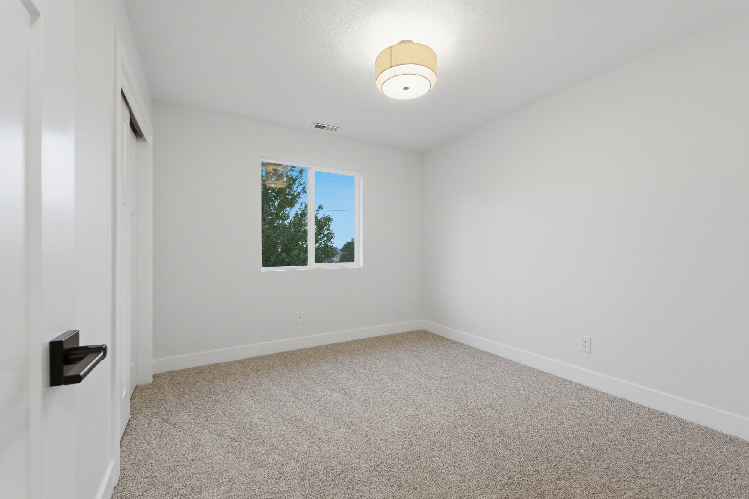 Room featuring neutral tone carpeting, white walls, and a single window with white trim