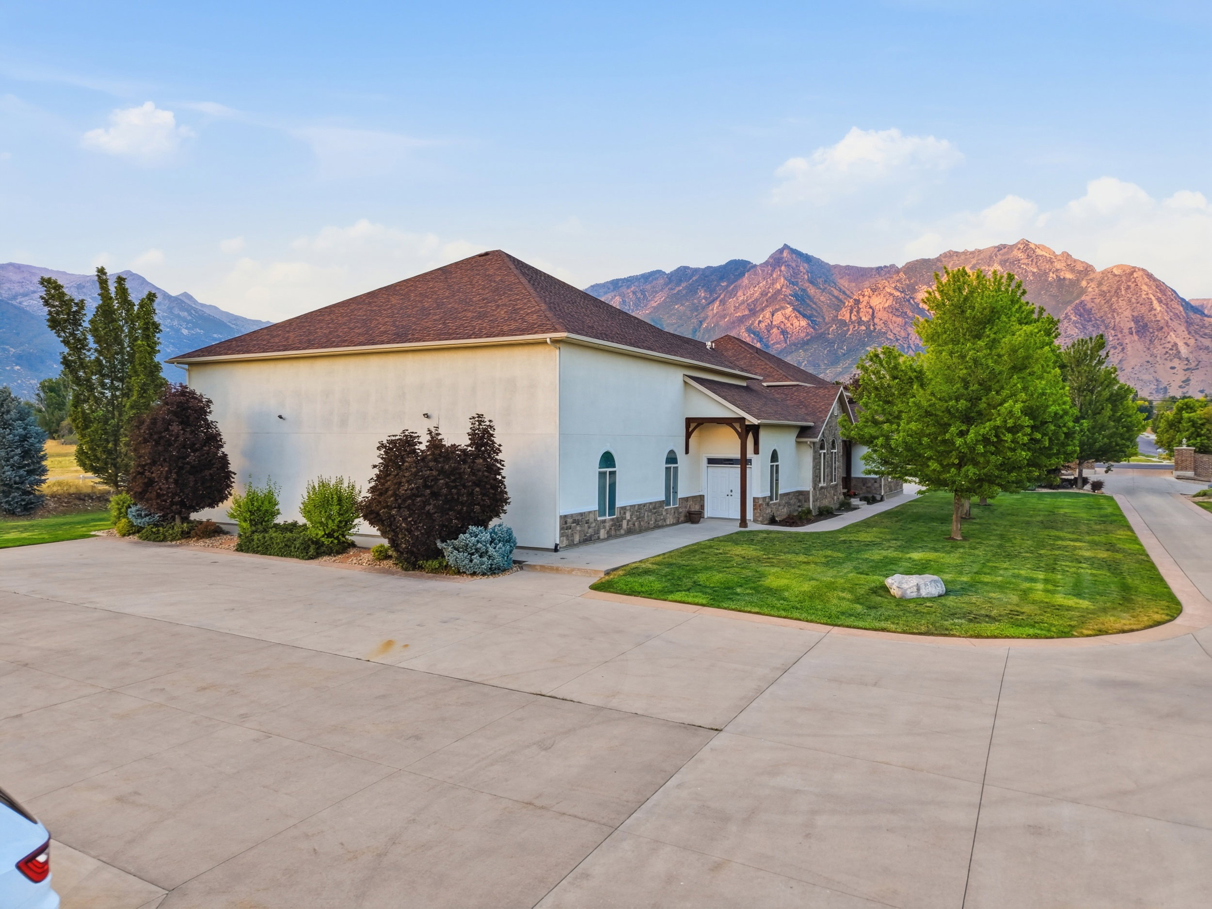 Contemporary stucco exterior with a stone veneer foundation, arched windows, and a prominent front entry with a wood-beam portico