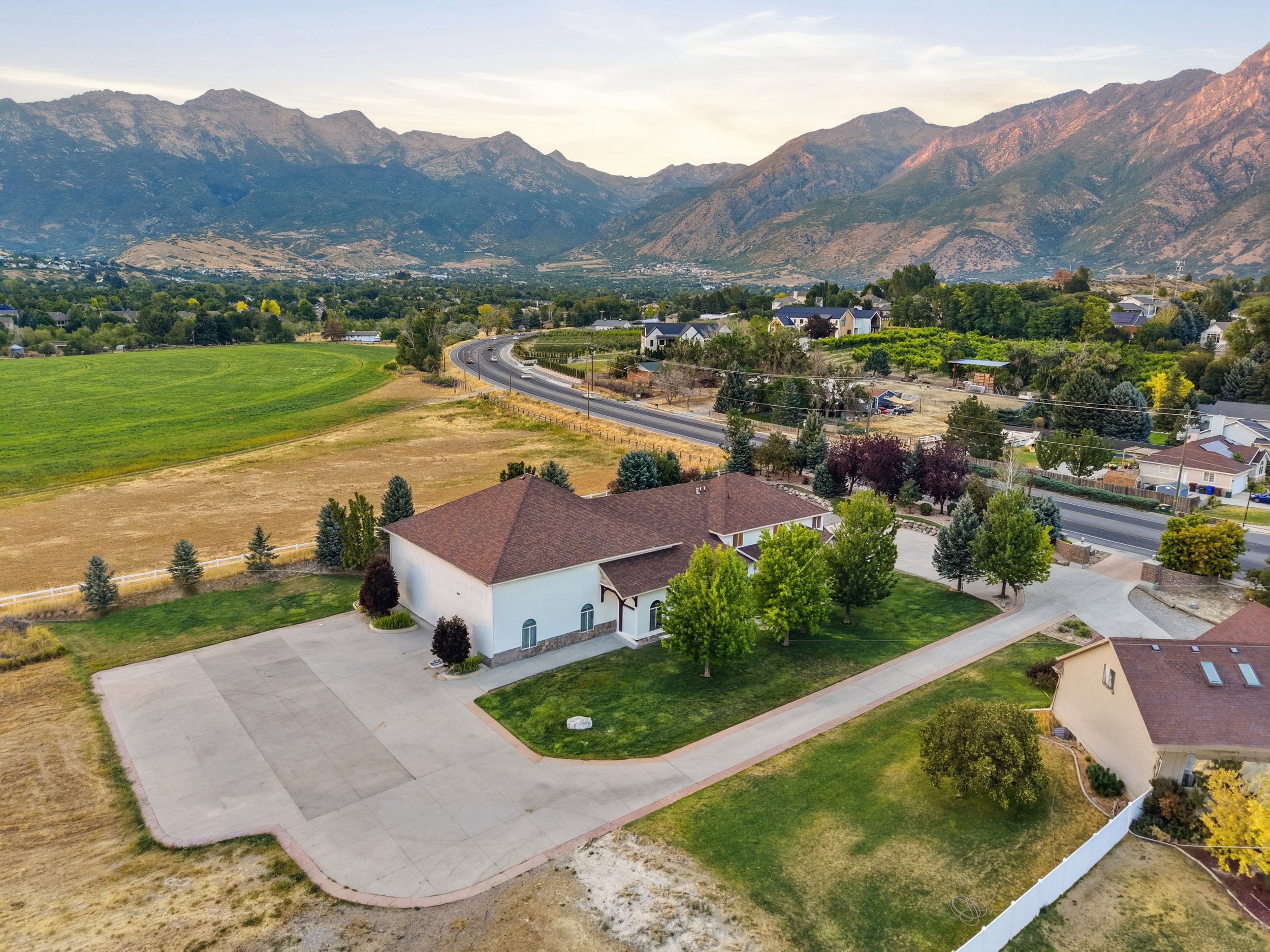 Expansive property featuring a large concrete driveway and surrounding green lawn