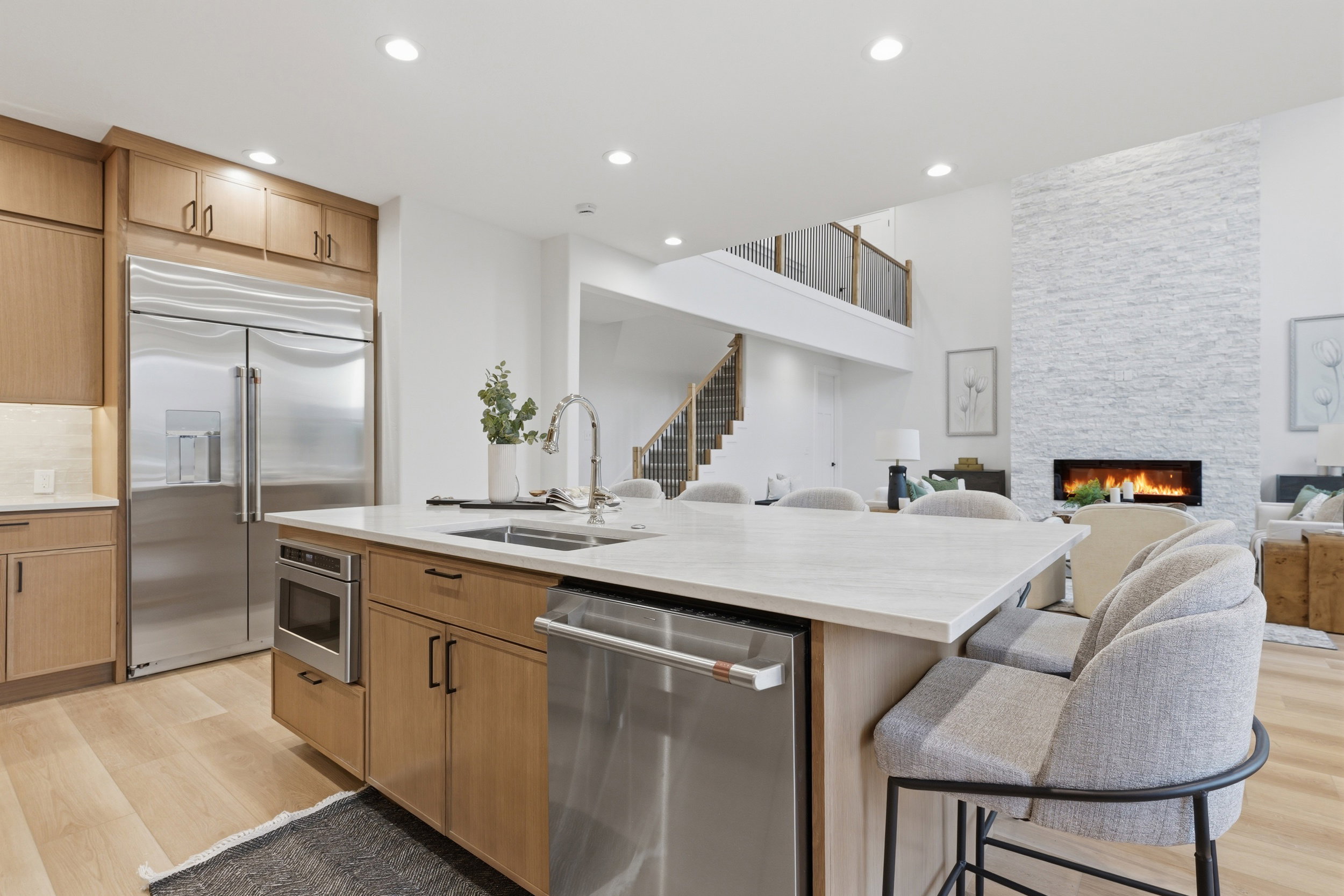 Open-concept kitchen with a large island featuring a sink, stainless steel dishwasher, and built-in microwave