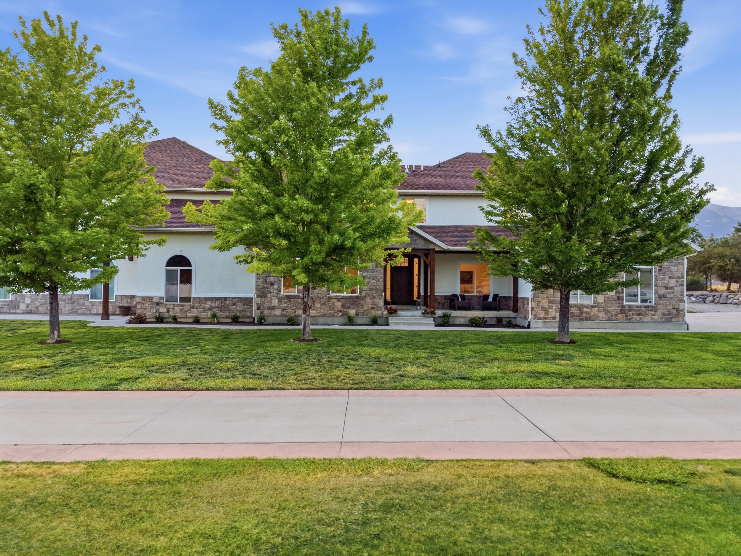 Exterior residence featuring a combination of stucco and stone siding, gabled roofline, and a covered porch entry