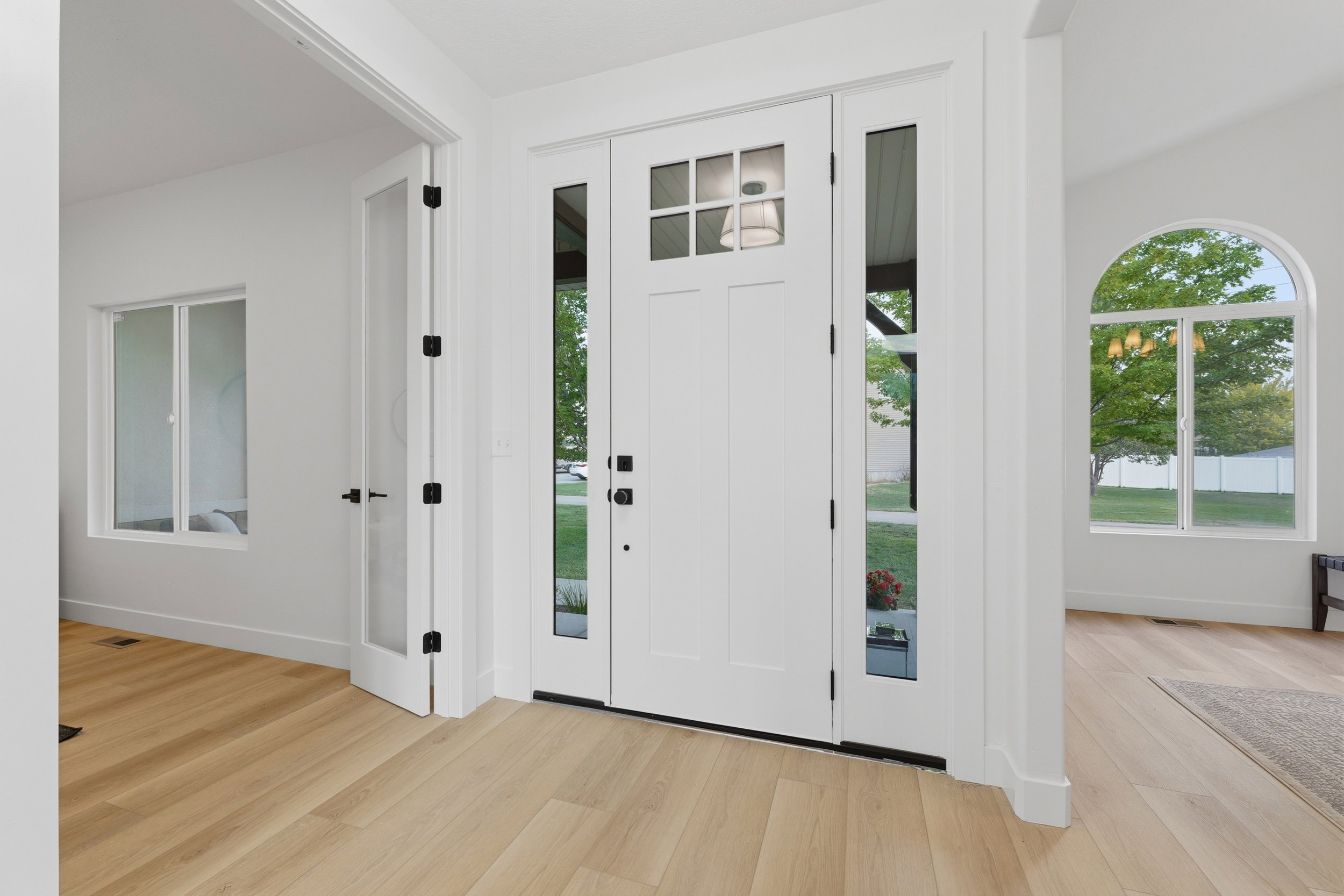Entryway with wood-finish flooring, a white paneled front door with glass inserts, and two clear glass sidelights