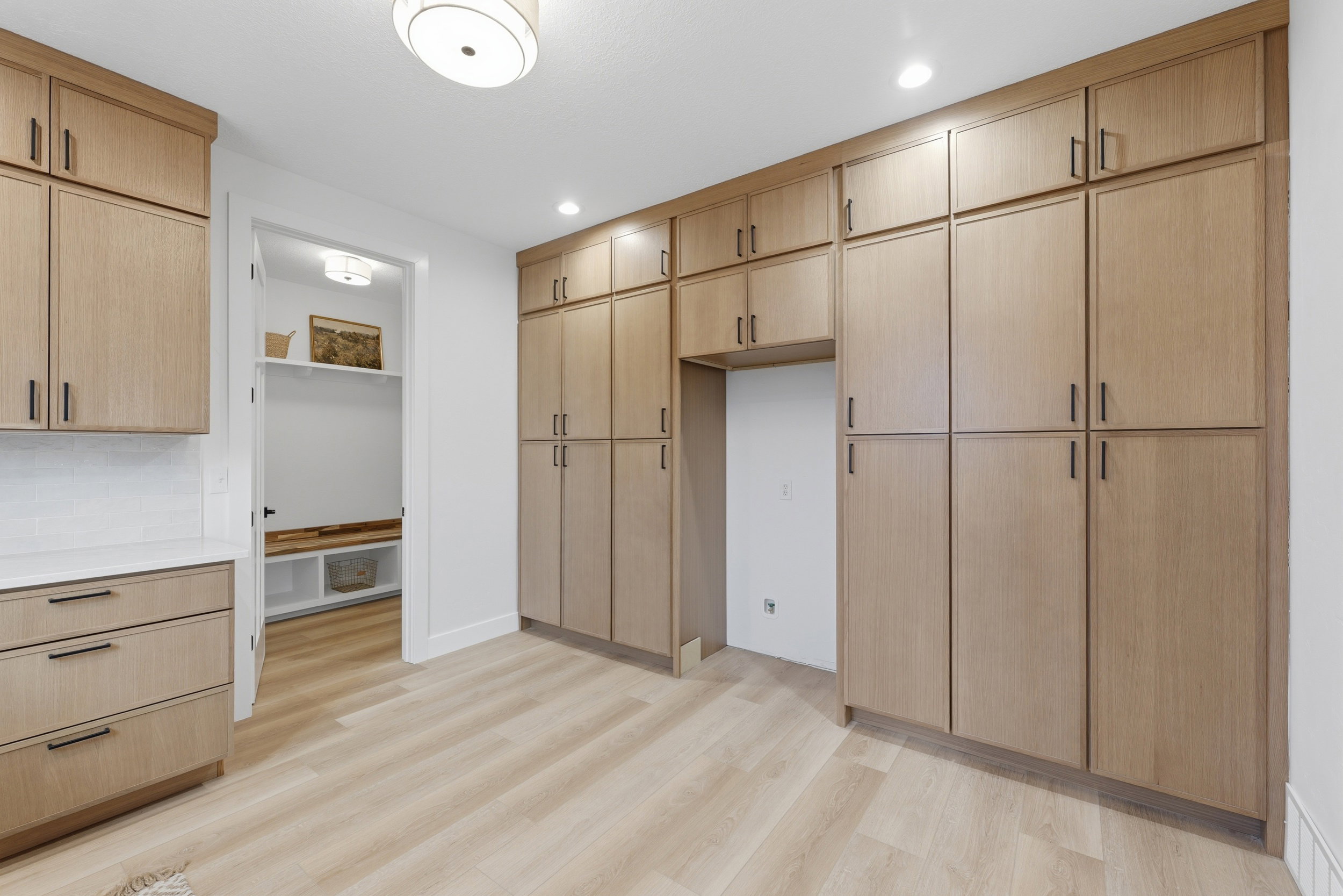 Extensive built-in cabinetry with light wood-finish doors and matte black hardware
