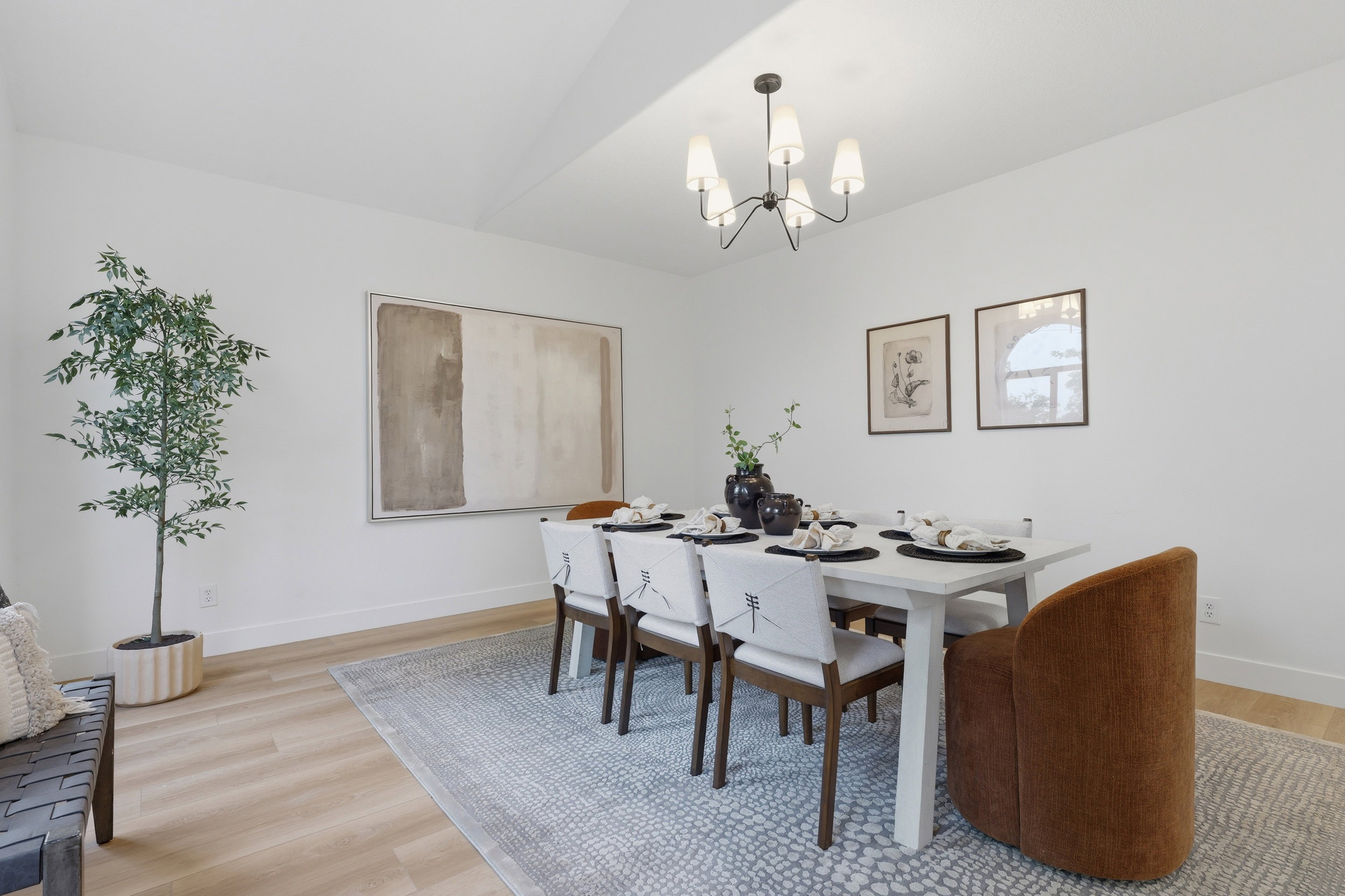 Spacious room featuring light wood-finish flooring, a contemporary chandelier, white walls, and a decorative area rug