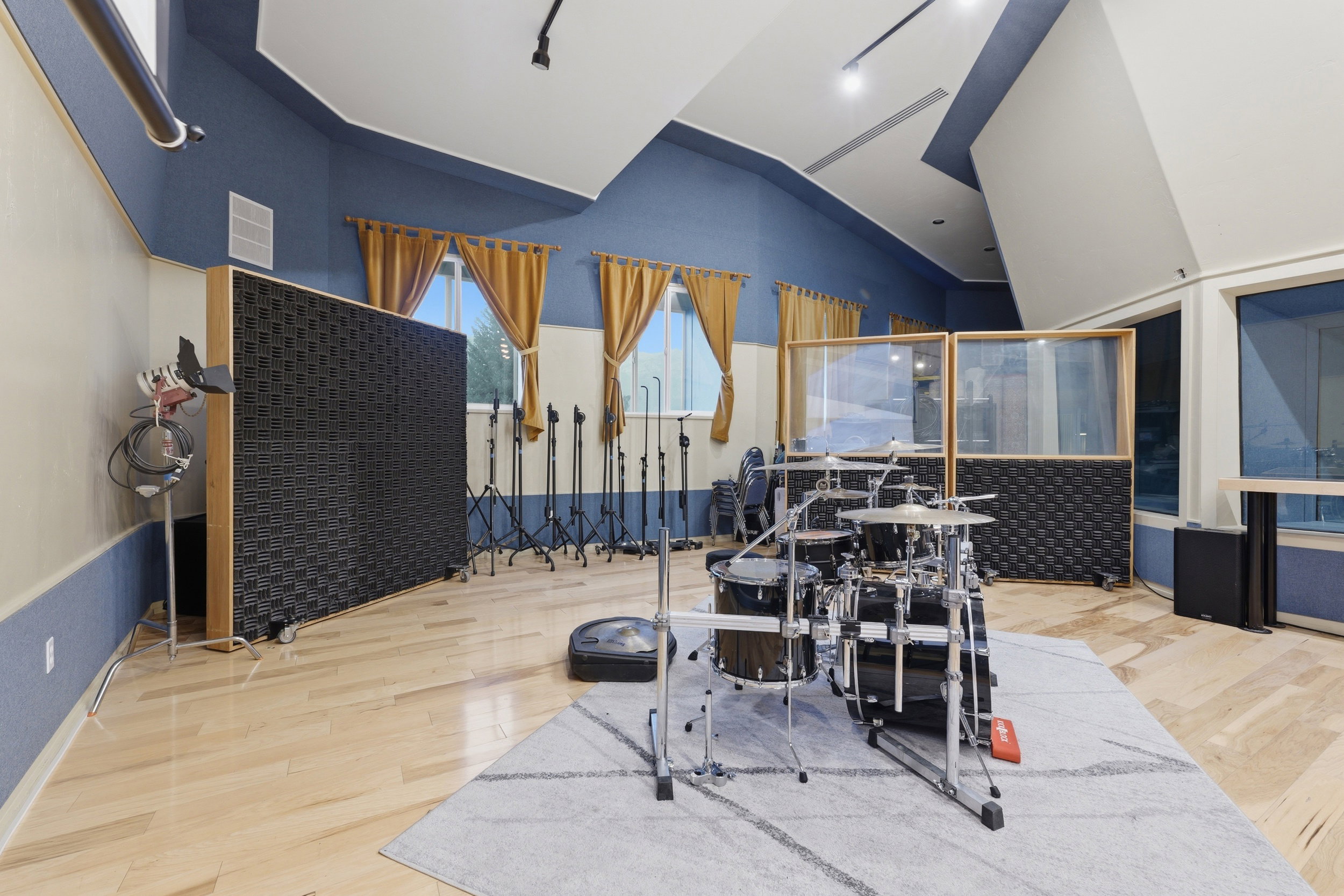 Dedicated studio space featuring wood-finish flooring, acoustic wall panels, track lighting, and architectural ceiling details