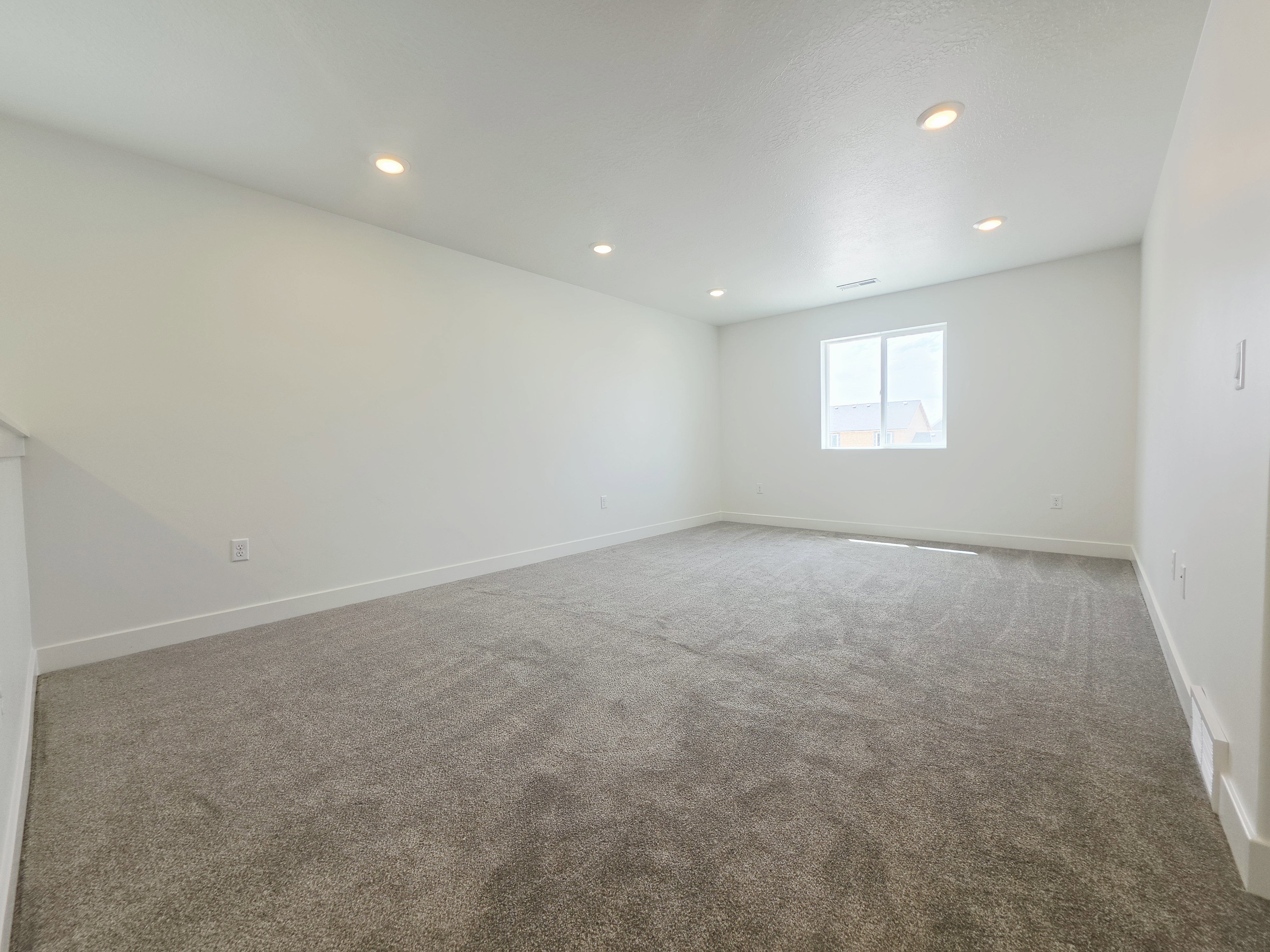 Spacious room featuring neutral carpeting and white walls