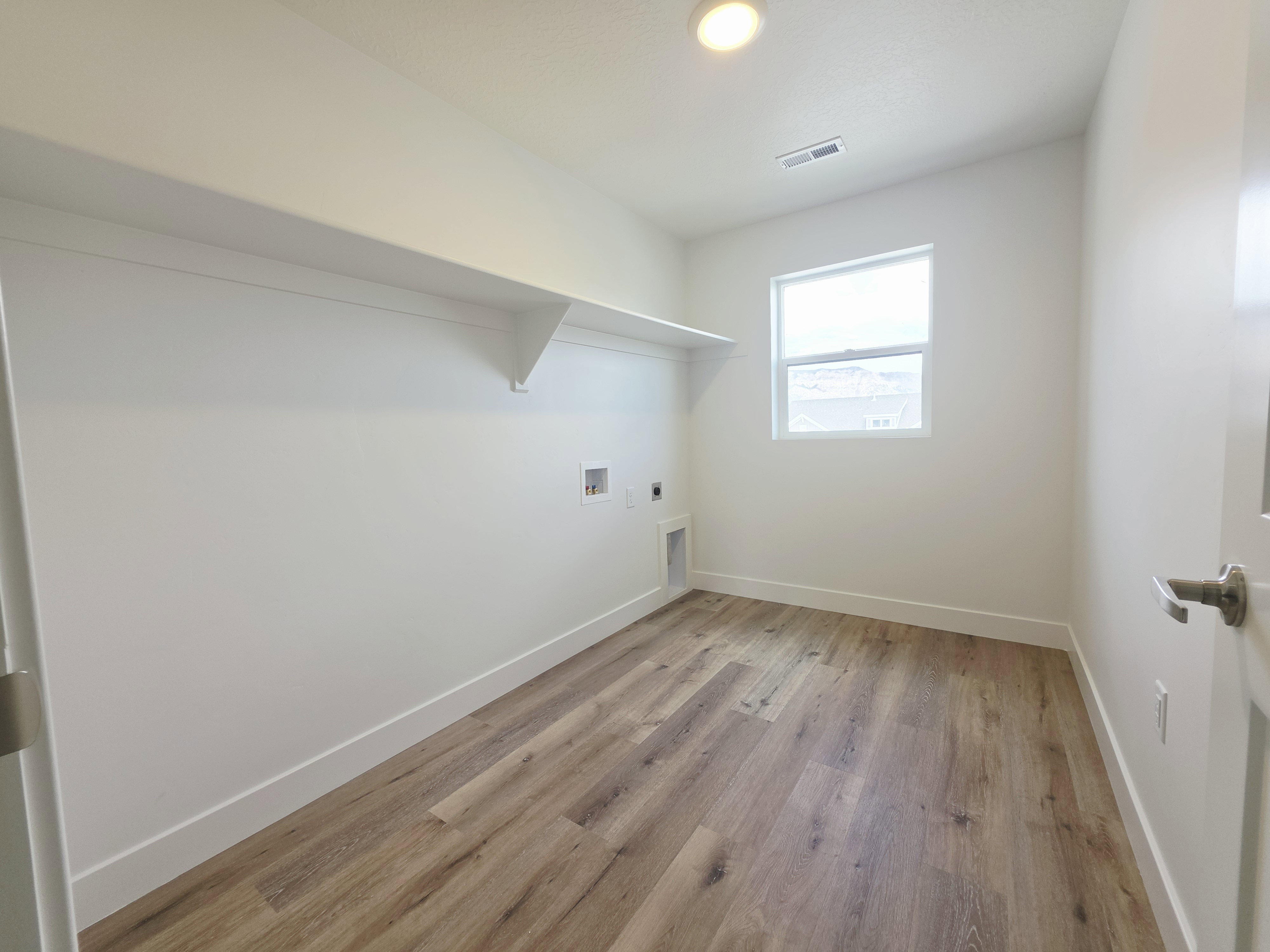 Laundry area featuring wood-finish flooring, white walls, and a recessed ceiling light