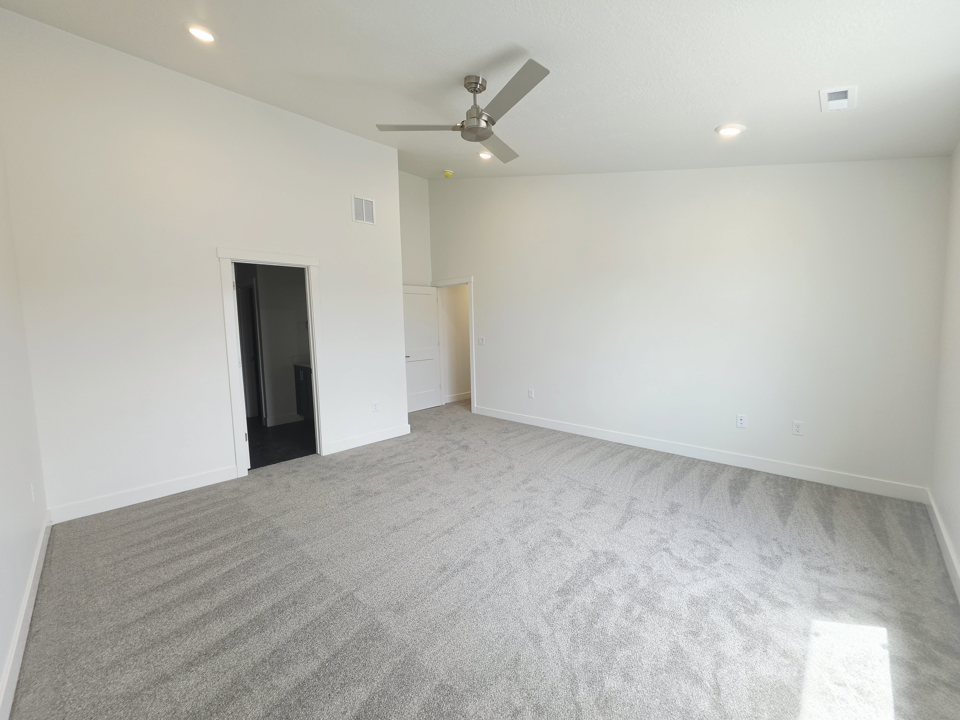 Spacious interior room featuring vaulted ceilings, recessed lighting, and a contemporary ceiling fan